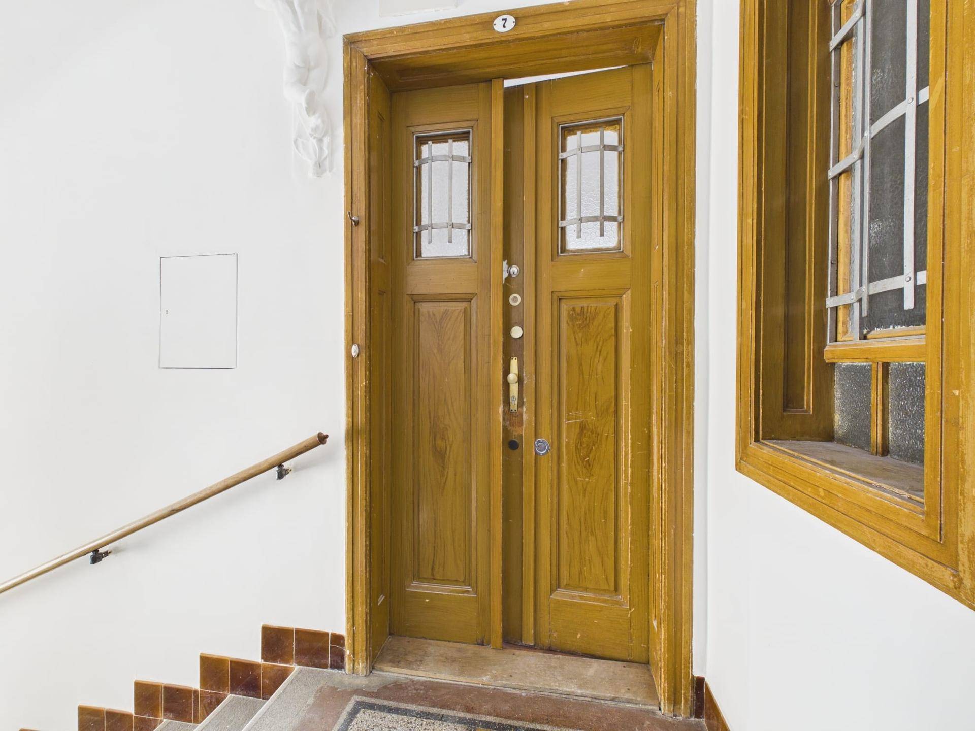 Holzeingangstür mit Glaseinsätzen und der Nummer 7 im Treppenhaus eines Altbaus.