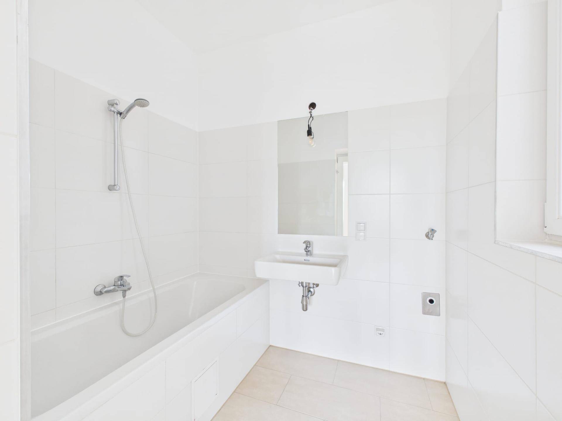 Modernes, hell gefliestes Badezimmer mit Badewanne, Dusche und Waschbecken.
