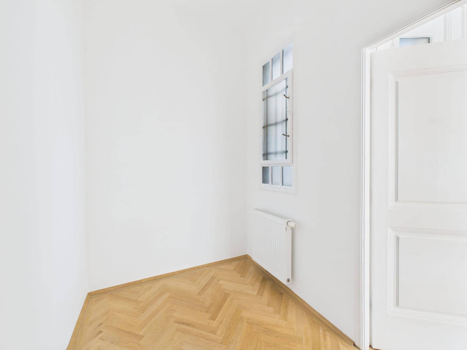 Kleiner, heller Bereich mit Fenster und Heizkörper, ausgestattet mit Fischgrätparkett.