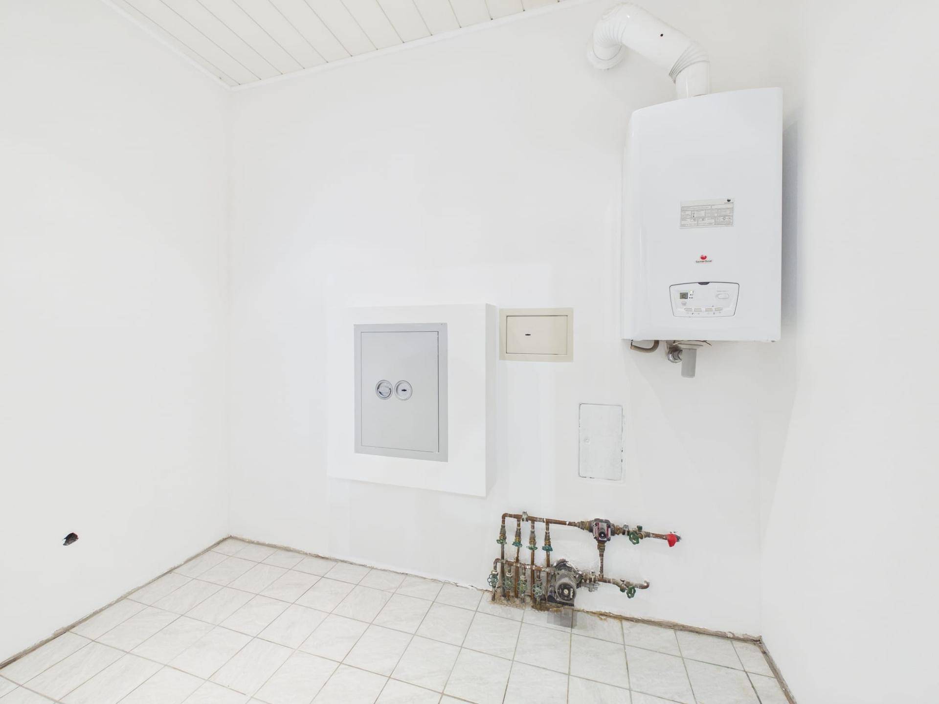 Heller Hauswirtschaftsraum mit Heizungsanlage und Fliesenboden.