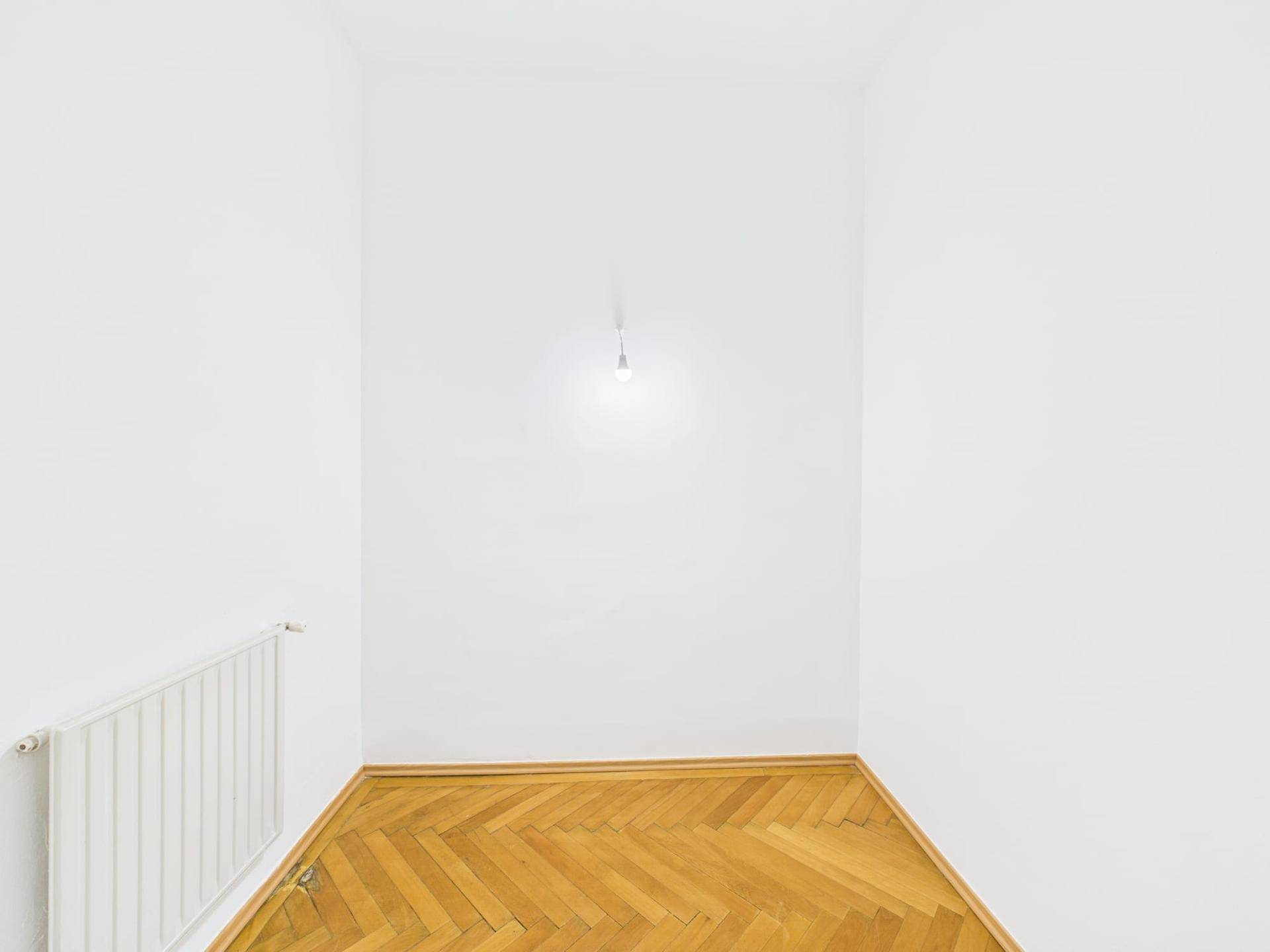 Kleiner, heller Raum mit Fischgrätparkett und weiß gestrichenen Wänden.