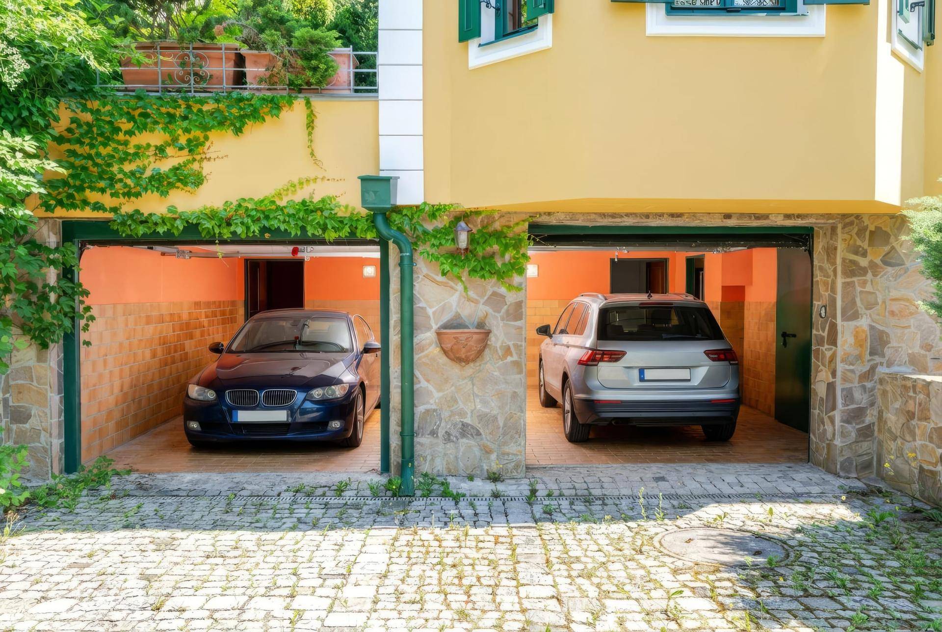 Offene Doppelgarage mit zwei geparkten Autos und Steinverkleidung, gut beleuchtet.