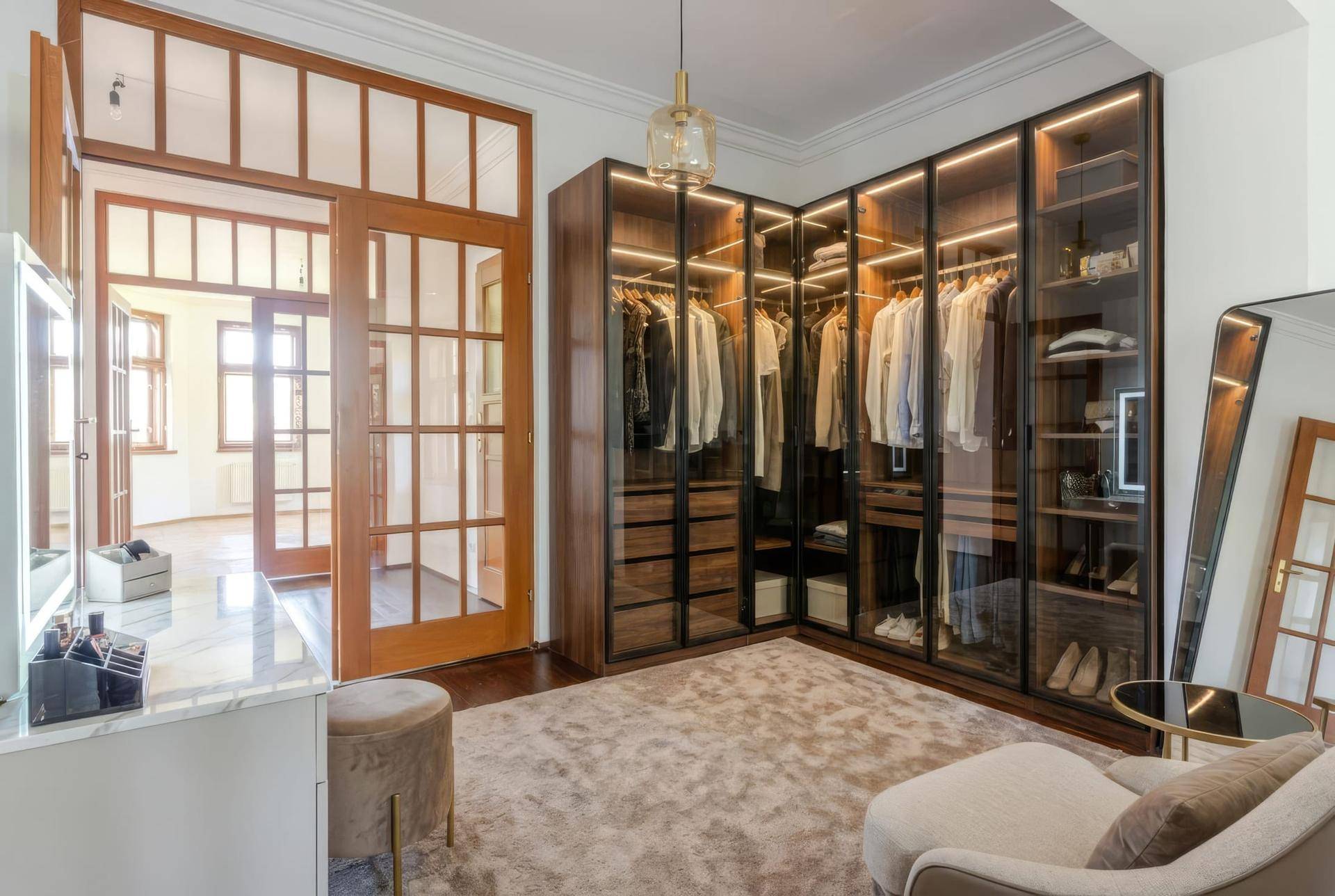Elegantes Ankleidezimmer mit beleuchteten Schränken, Spiegel und Sitzgelegenheiten.