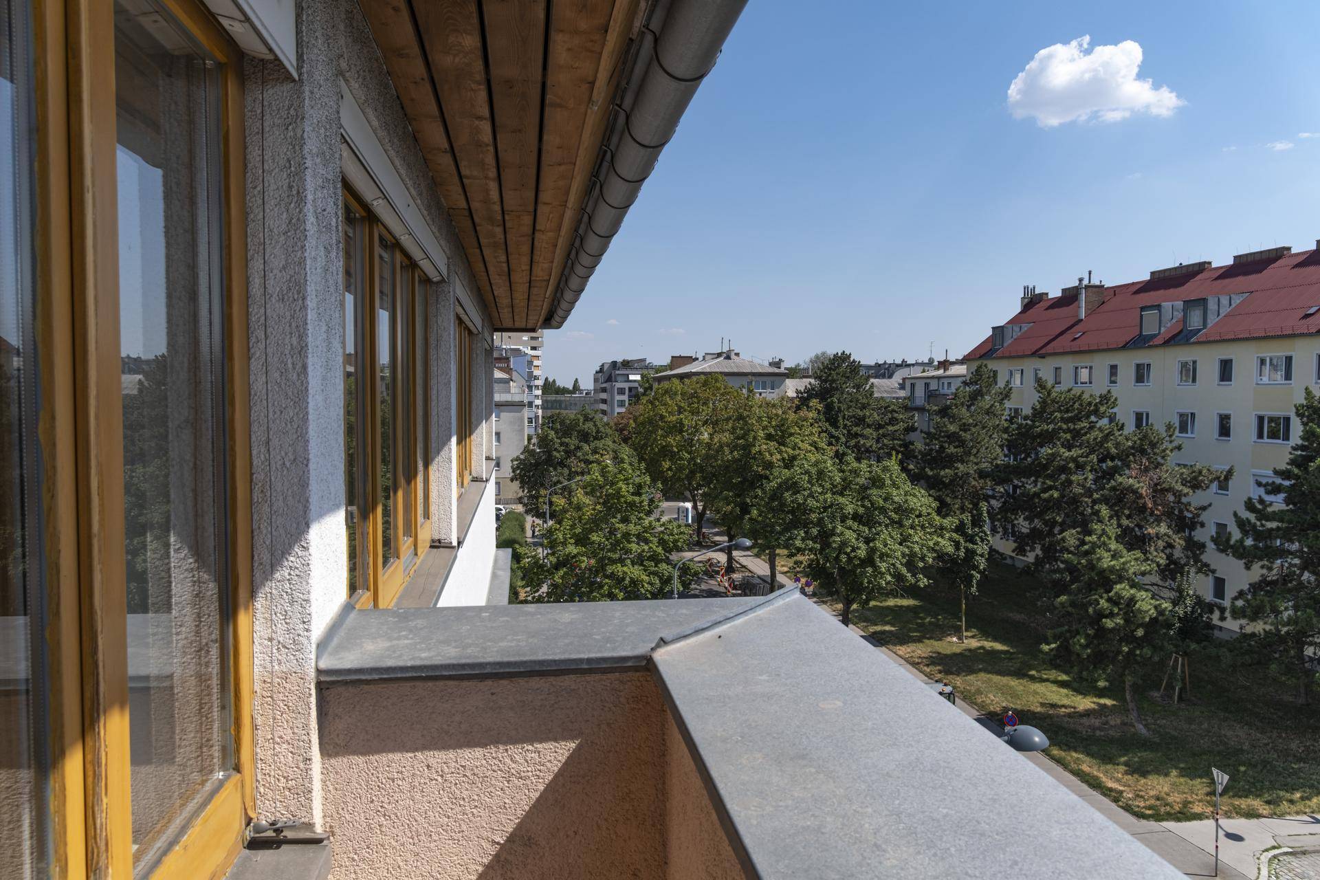 Aussicht von einem Balkon auf ein Wohnviertel mit Bäumen und einem weiteren Gebäude.