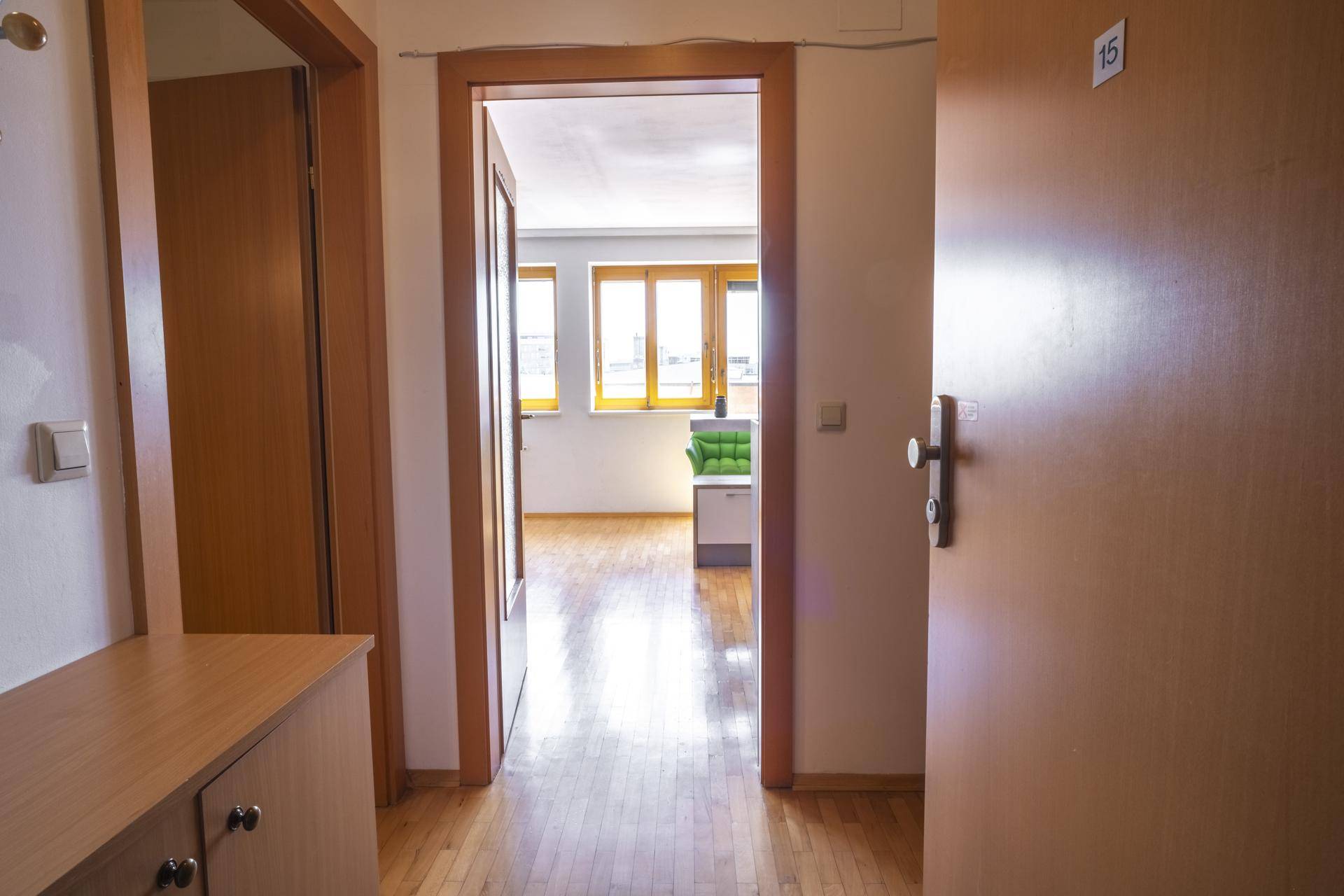 Heller Eingangsbereich mit Holzboden und Blick durch eine Glastür in den Wohnbereich.