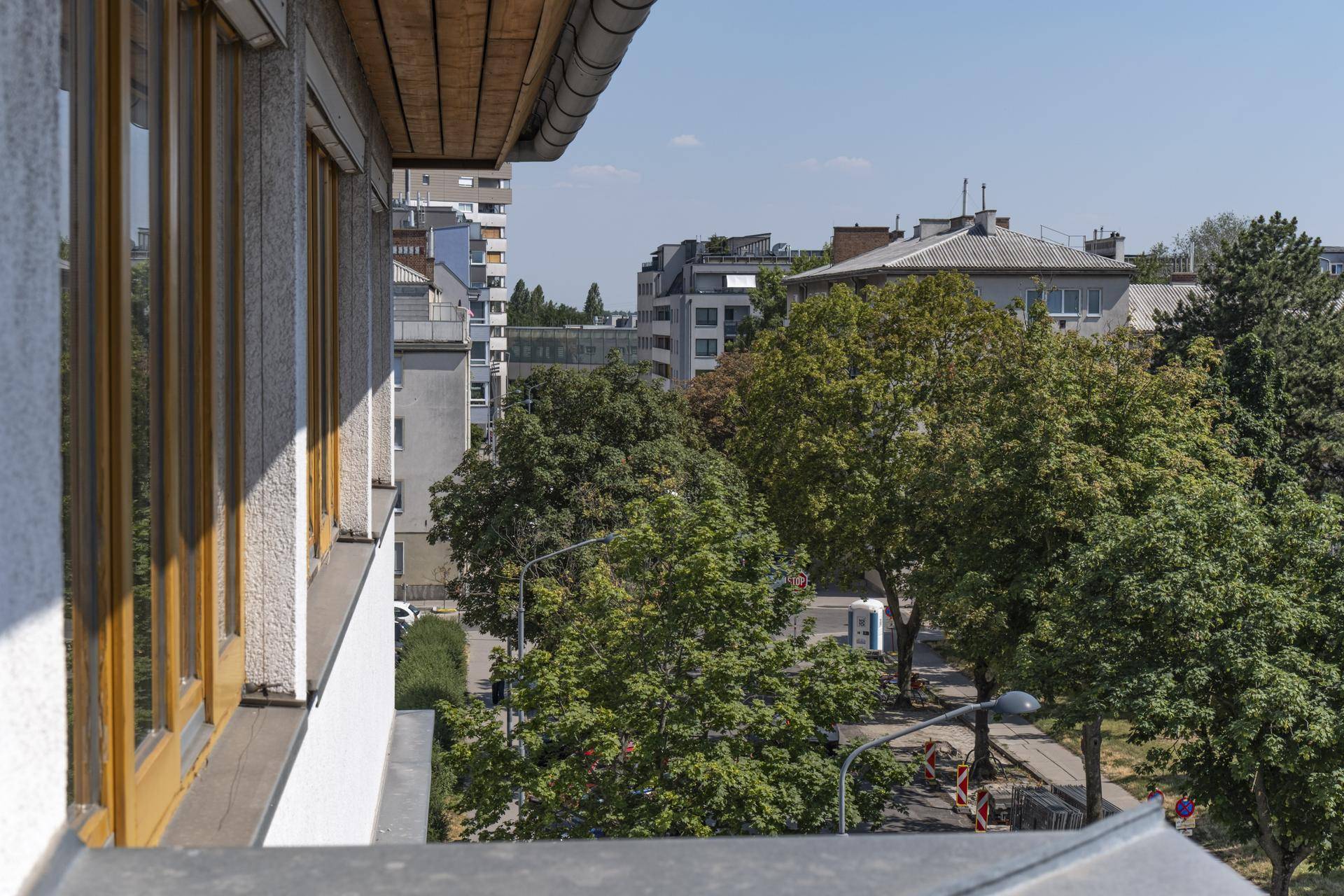 Detailansicht der grünen Umgebung und der städtischen Bebauung von einem Balkon aus.