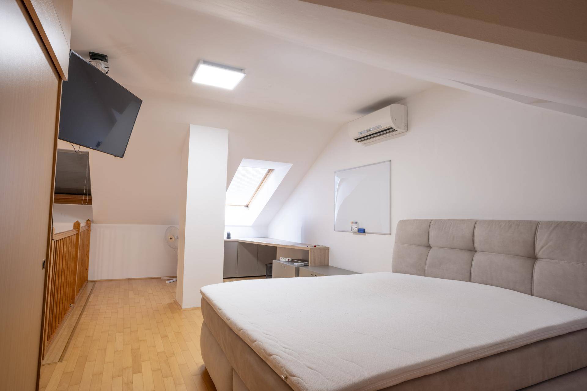 Gemütliches Schlafzimmer im Dachgeschoss mit Doppelbett, Dachfenster und Klimaanlage.