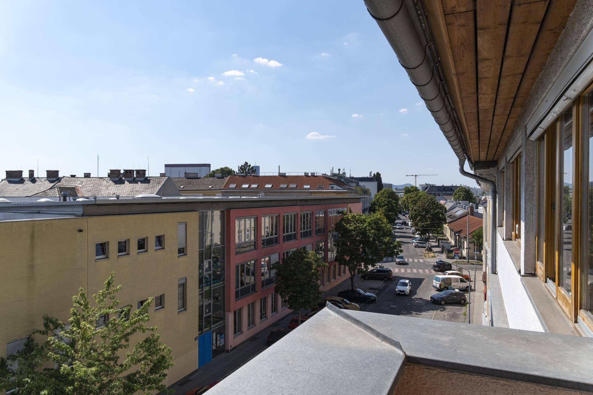Weitläufiger Stadtblick von einem Balkon oder einer Terrasse mit Bäumen und Gebäuden.