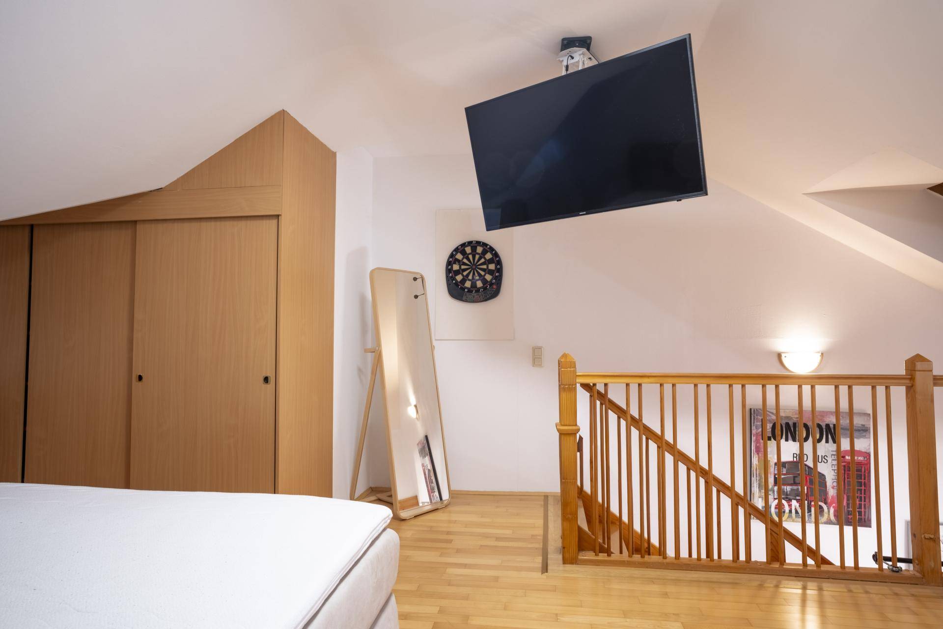 Schlafzimmer im Dachgeschoss mit Holzboden, Einbauschränken und Zugang zur Treppe.