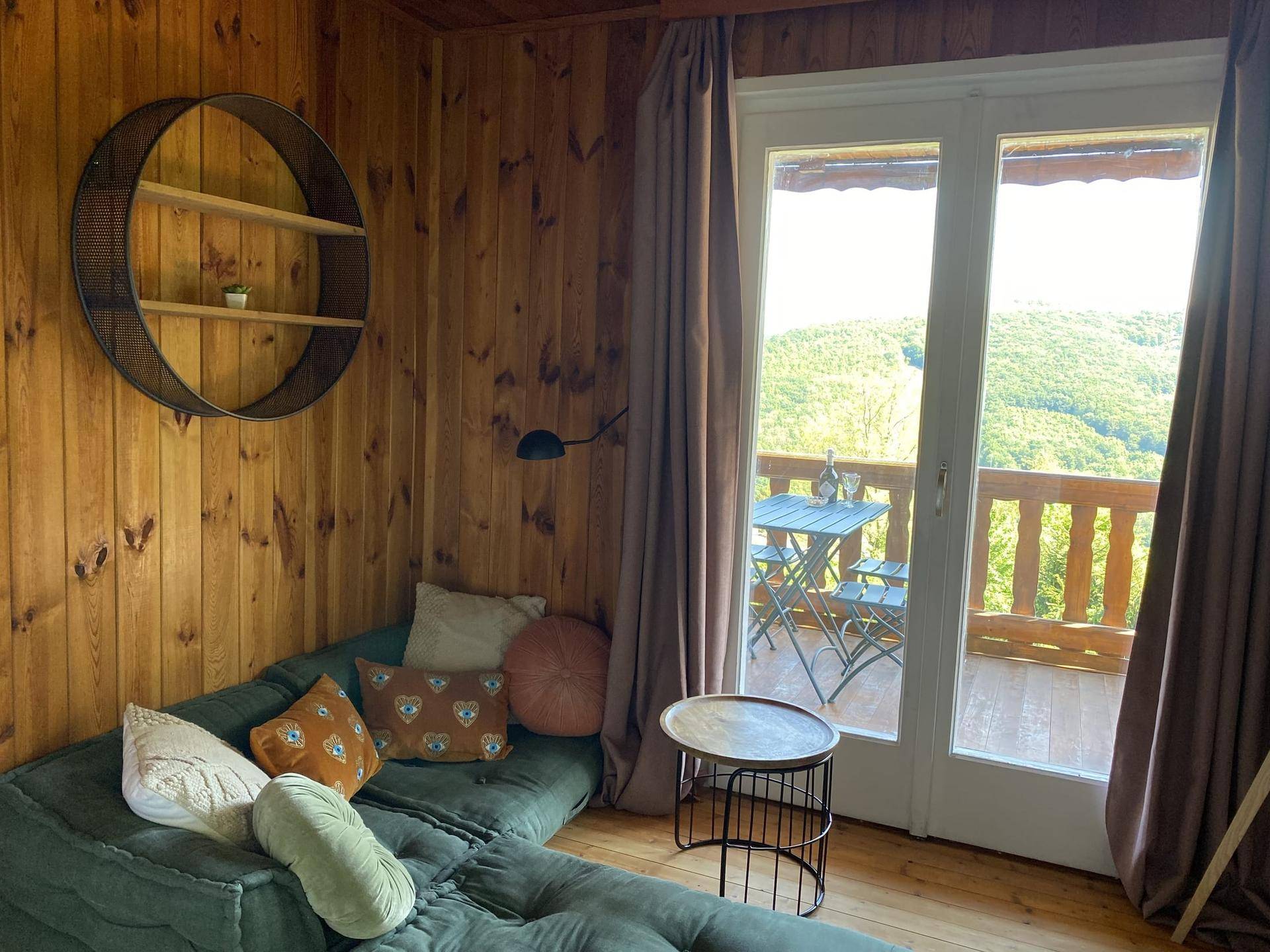 Gemütlicher Wohnbereich mit Holzwänden und Zugang zu einem Balkon mit Panoramablick.