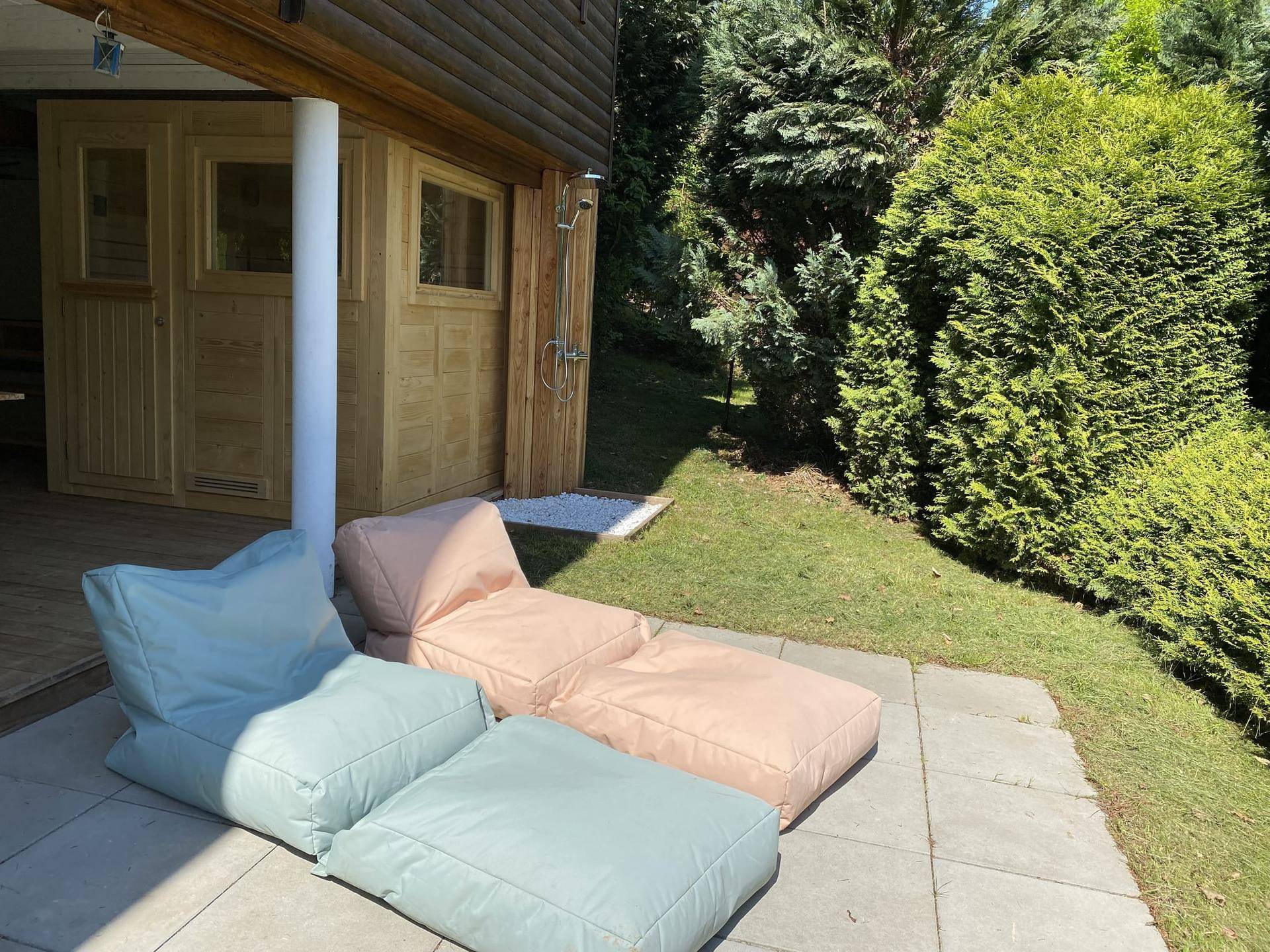 Entspannungsbereich im Garten mit Liegestühlen und Zugang zur Sauna.