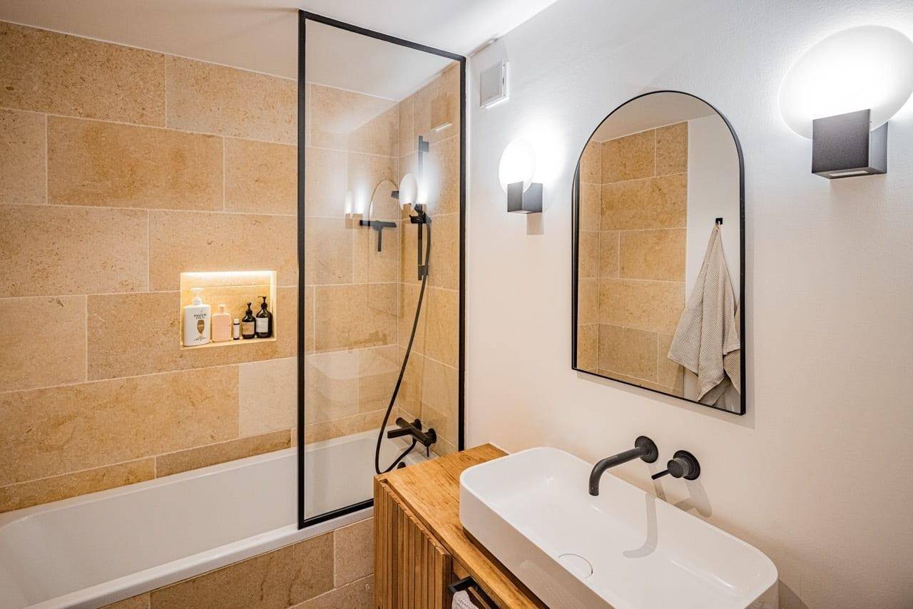 Modernes Badezimmer mit Badewanne, Duschabtrennung und stilvollem Waschbecken.