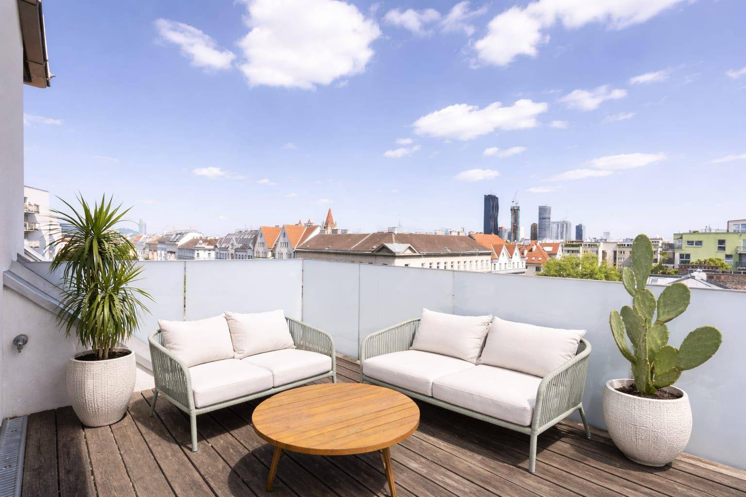 Dachterrasse mit Lounge-Möbeln, Pflanzen und weitem Blick über die Stadt.