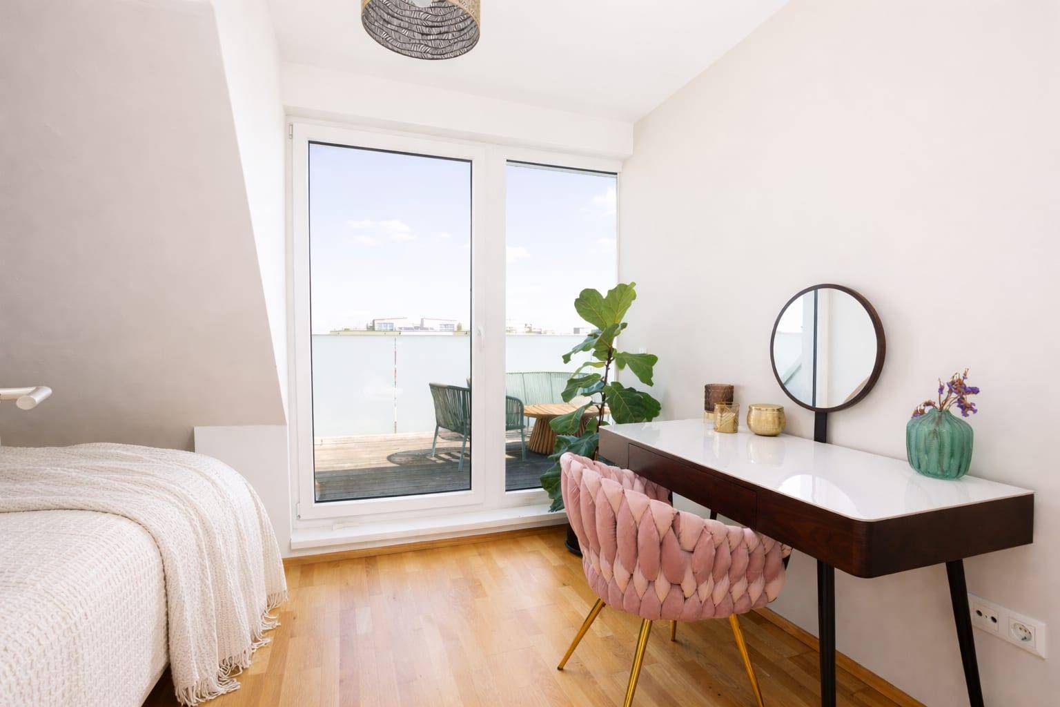 Helles Schlafzimmer mit Holzboden, Schminktisch und Zugang zur Dachterrasse.