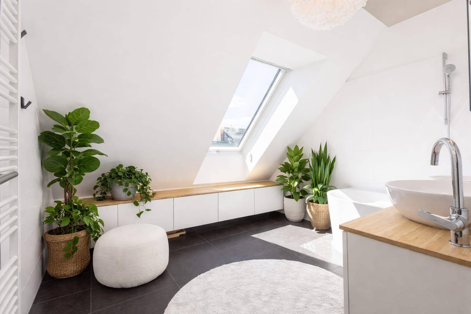 Modernes Badezimmer mit Pflanzen, Badewanne und Waschtisch unter Dachfenster.