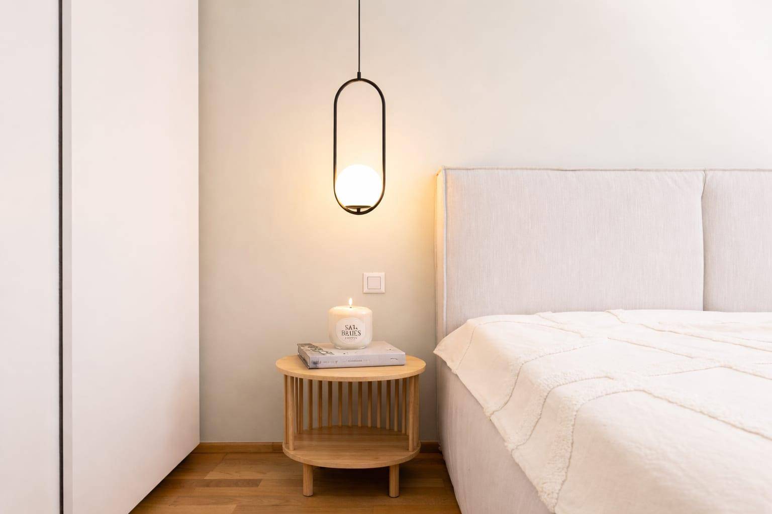 Detailansicht eines Schlafzimmers mit Nachttisch, Lampe und gemütlichem Bett.