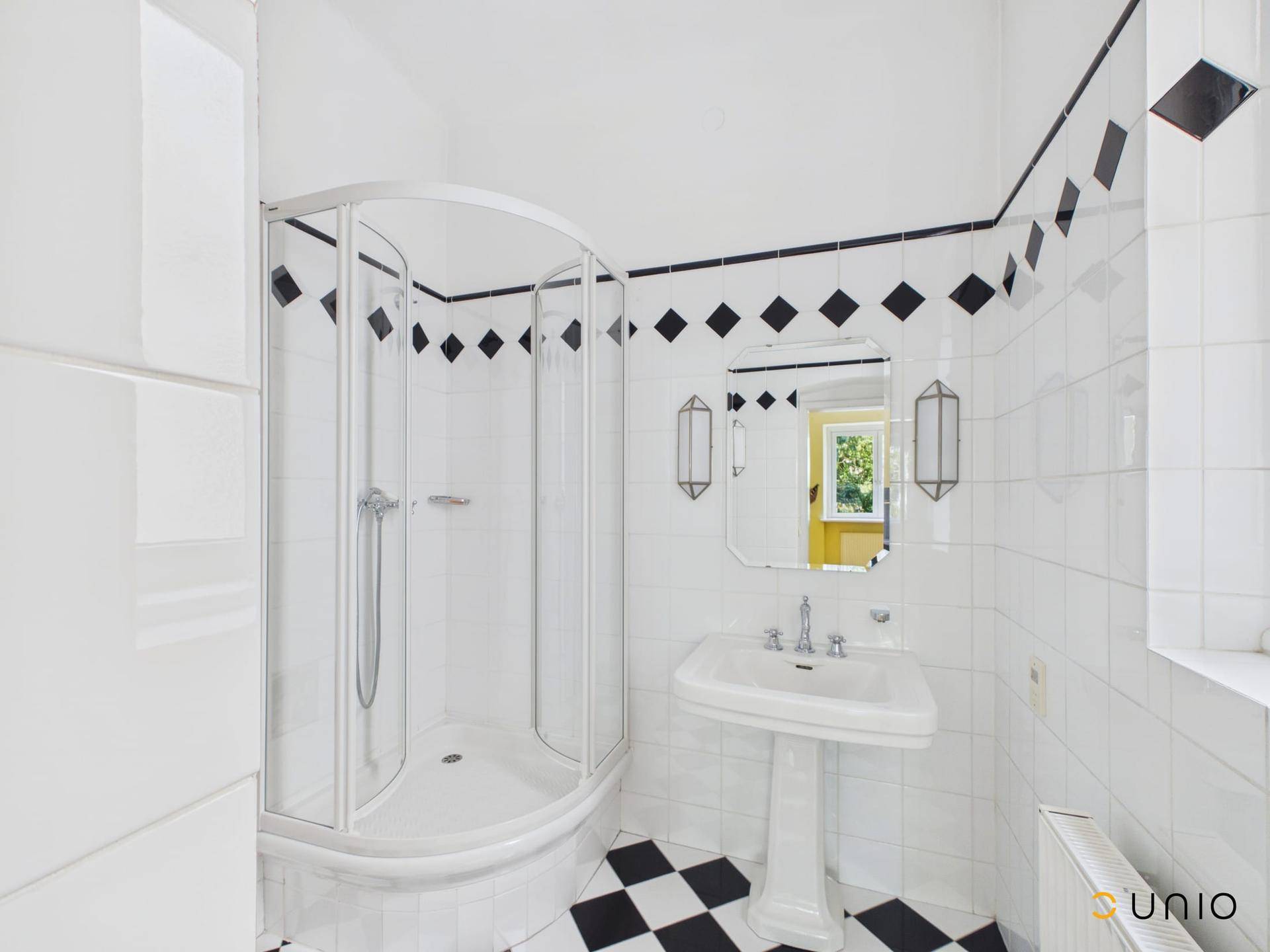Badezimmer mit schwarz-weißen Fliesen, Duschkabine und Standwaschbecken im Vintage-Stil.