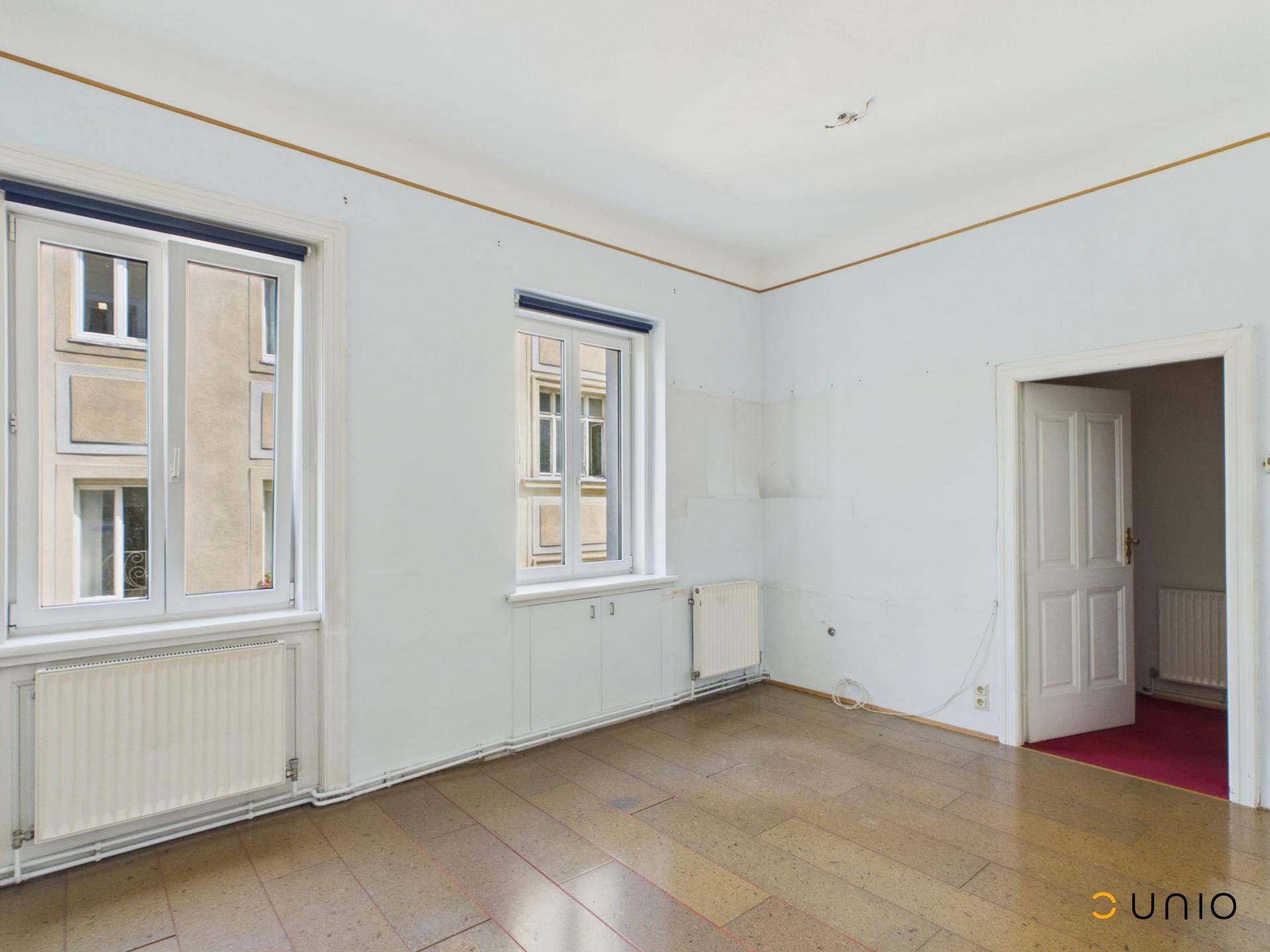 Geräumiges Zimmer mit zwei Fenstern und Parkettboden, bereit zur individuellen Gestaltung.
