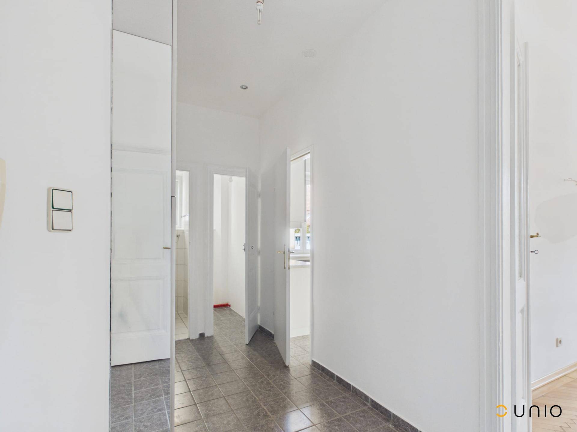 Heller Flur mit Fliesenboden und Zugang zu mehreren Zimmern der Wohnung.