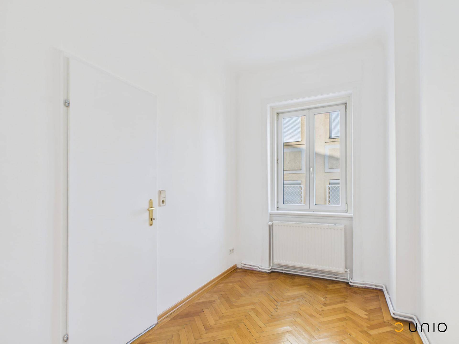 Kleines Zimmer mit Fischgrätparkett und Fenster, geeignet als Schlaf- oder Arbeitszimmer.