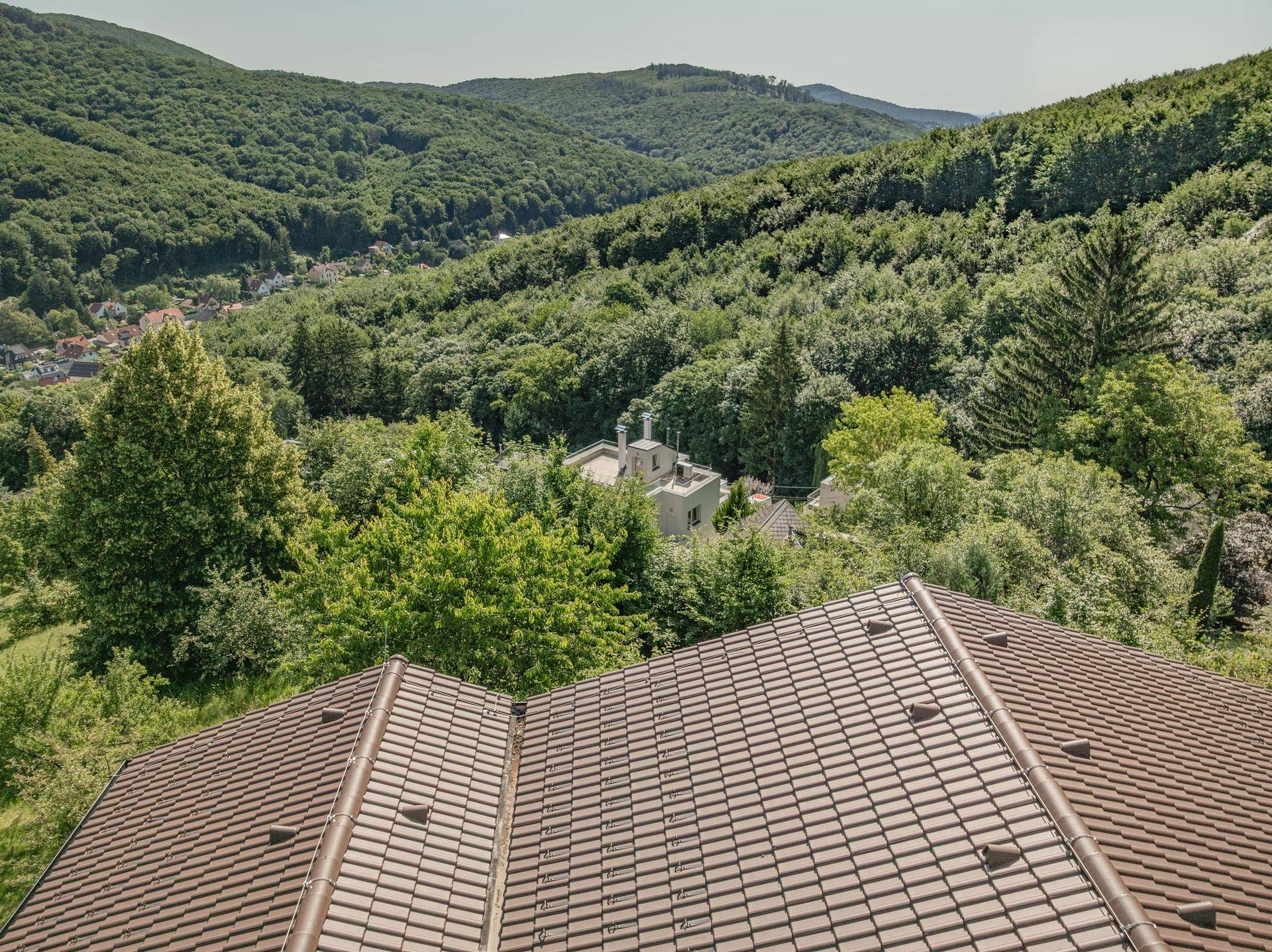 Weitläufiger Blick über das Dach des Hauses auf die bewaldete Hügellandschaft.