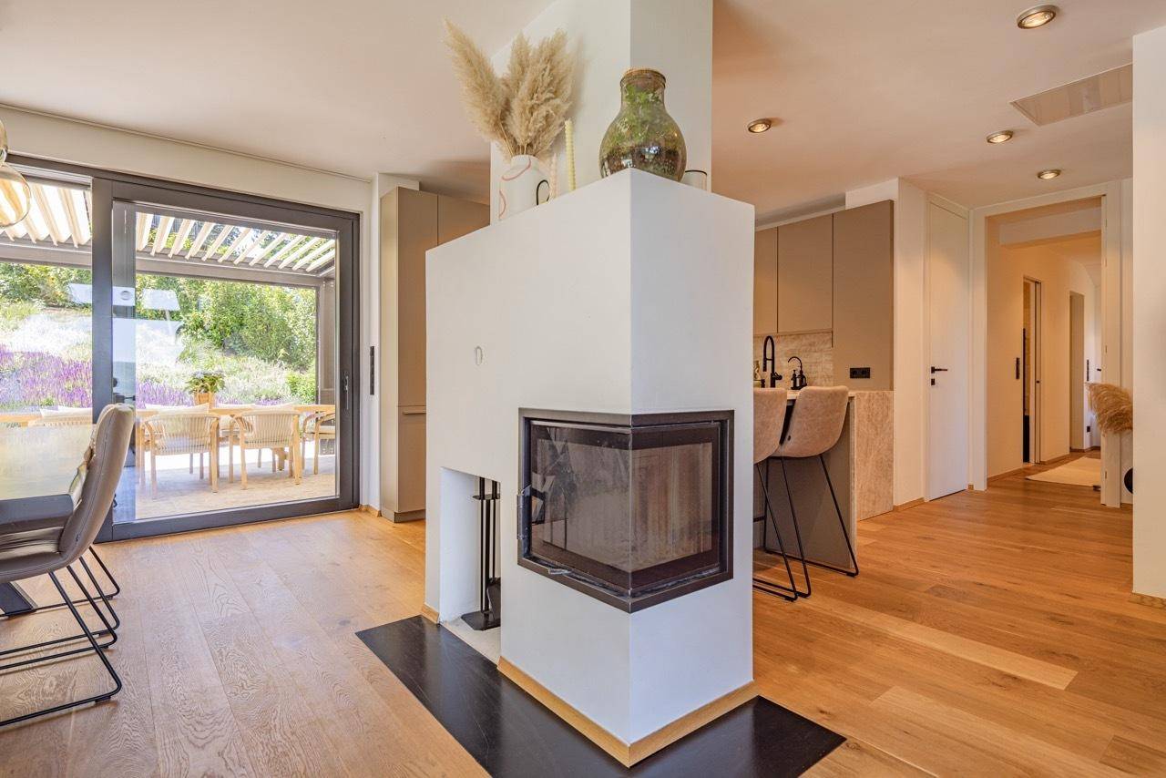 Heller Wohn- und Essbereich mit Kamin, Holzboden und Zugang zur Terrasse.