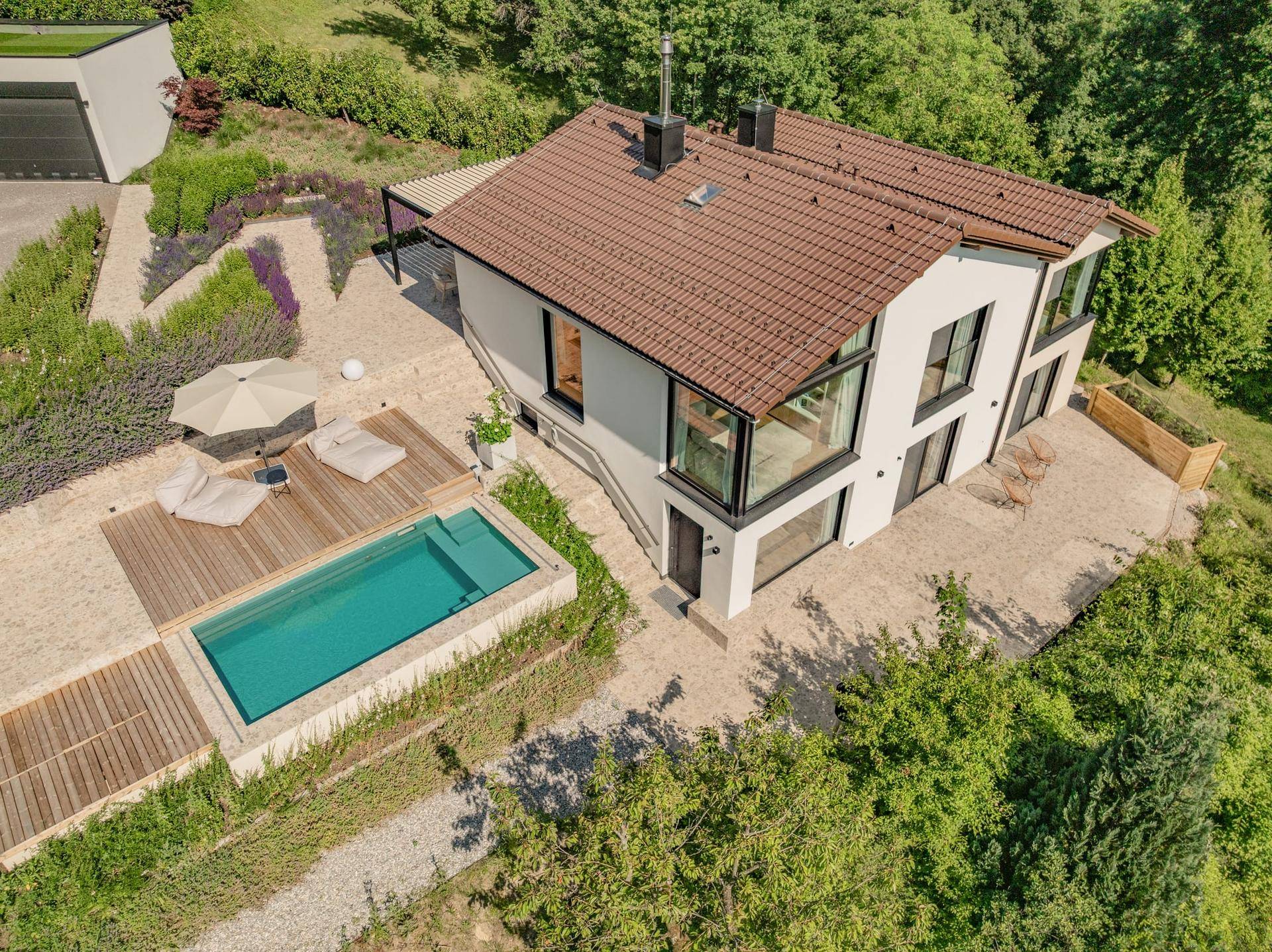 Luftaufnahme des modernen Hauses mit Pool, Terrasse und weitläufigem Gartenbereich.