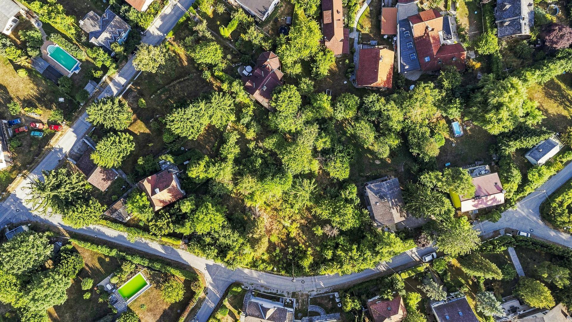 Detaillierte Luftaufnahme des großen, grünen Grundstücks, umgeben von Wohnhäusern und Straßen in einer bewaldeten Umgebung.