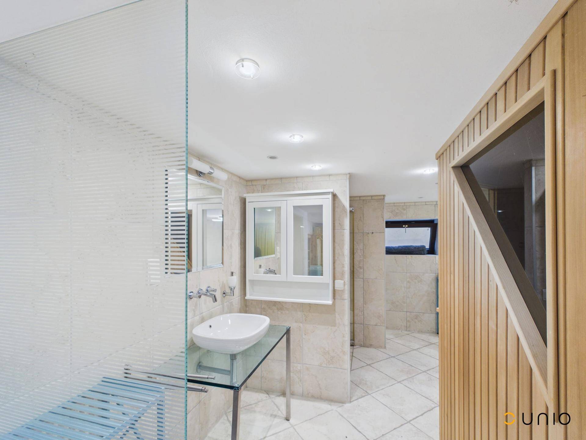Modernes Badezimmer mit begehbarer Dusche, Einzelwaschbecken und angrenzender Sauna.