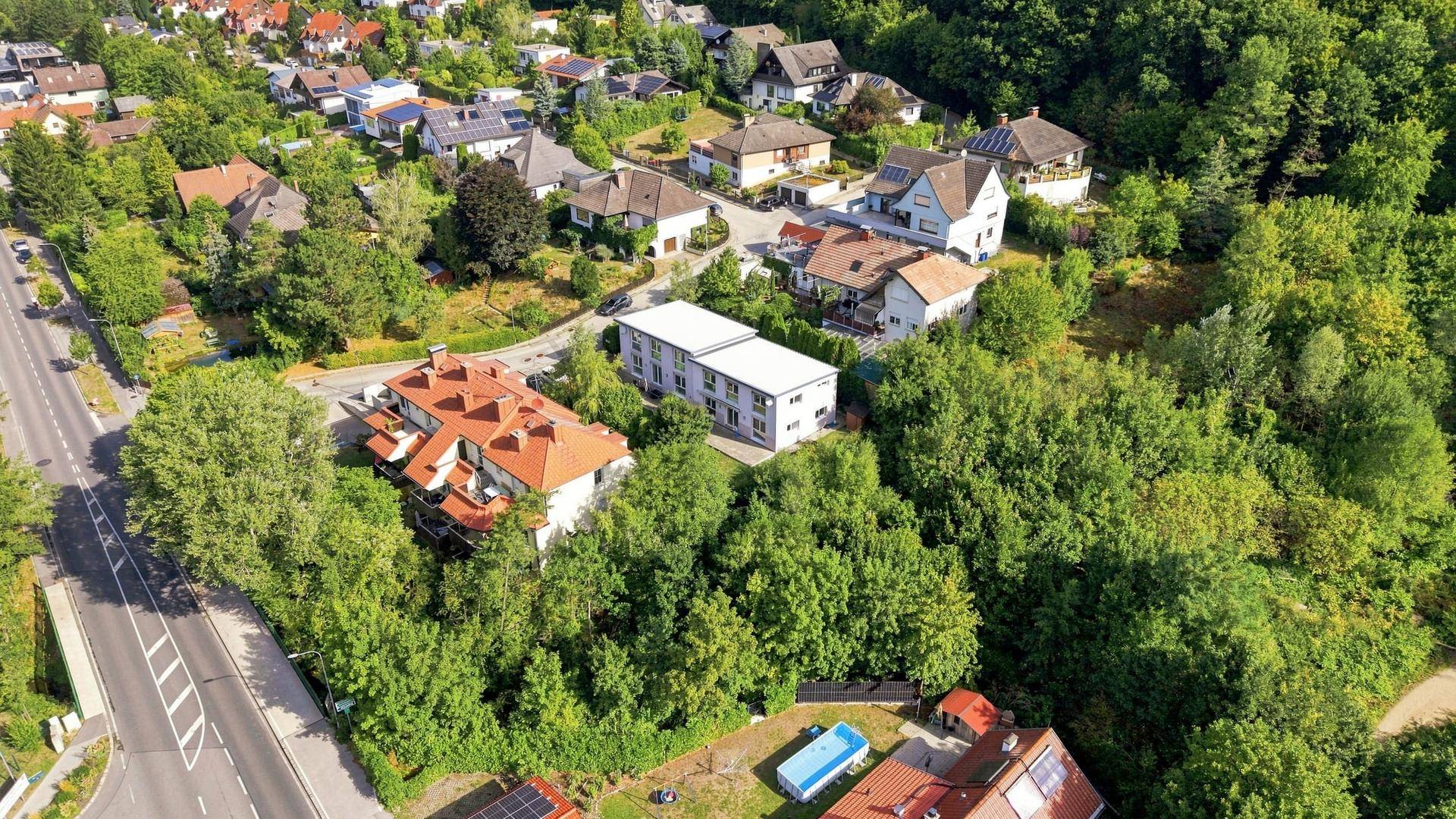 Luftaufnahme einer Wohnsiedlung mit viel Grün und umliegenden Wäldern.