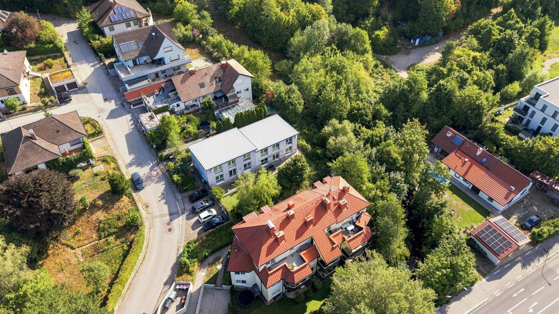 Weitläufige Luftaufnahme einer Wohngegend mit Einfamilienhäusern und viel Baumbestand.