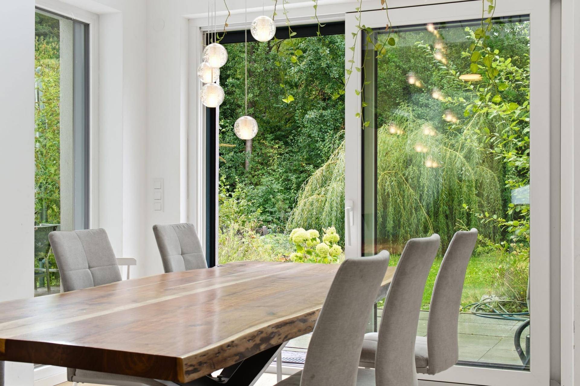 Heller Essbereich mit Holztisch und großen Schiebetüren zum grünen Garten.