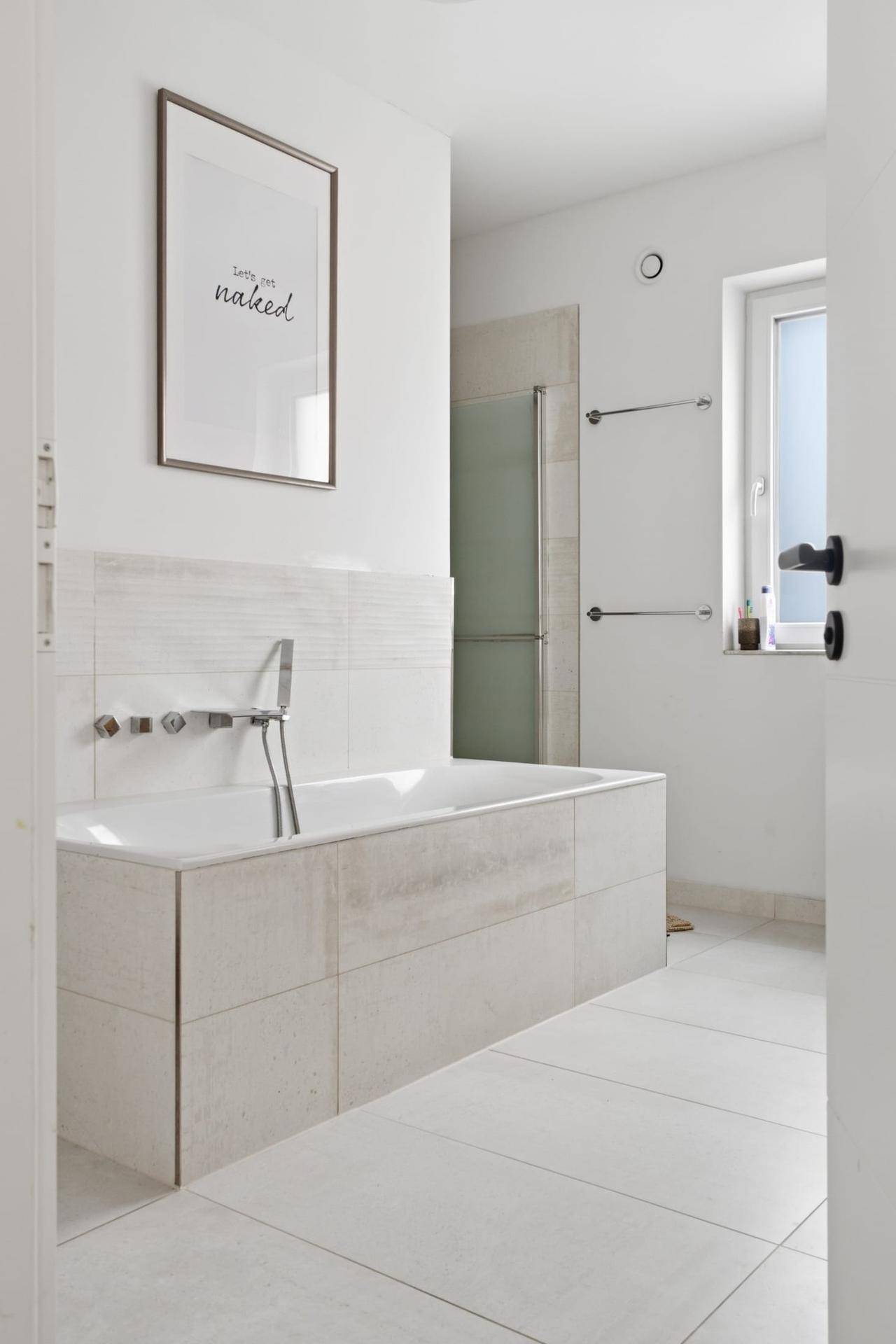 Modernes Badezimmer mit Badewanne, Fliesenboden und Fenster für Tageslicht.
