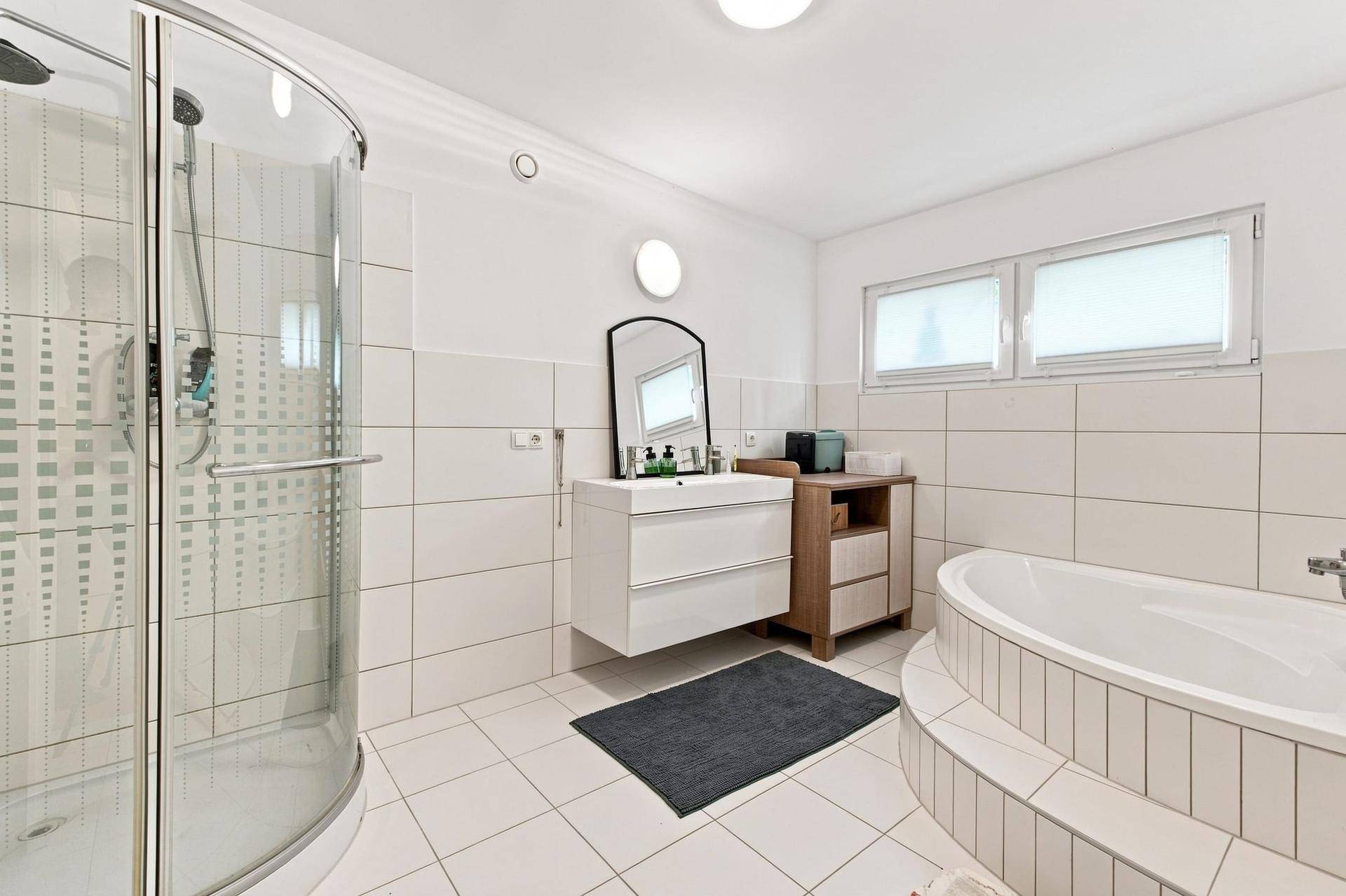 Modernes Badezimmer mit Dusche, Badewanne, Einzelwaschbecken und Fenster.