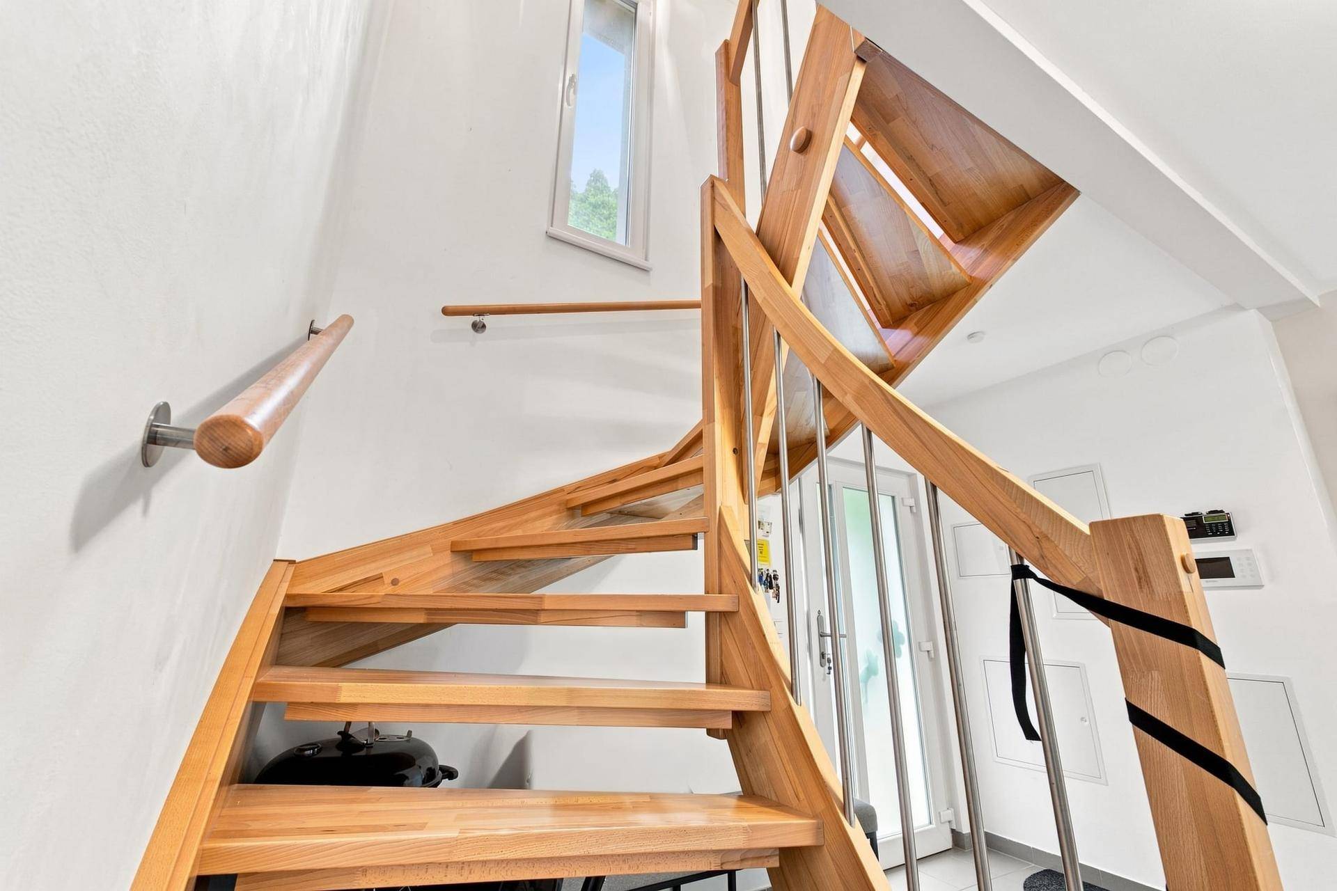 Helle Holztreppe mit Edelstahlgeländer, die die verschiedenen Ebenen des Hauses verbindet.
