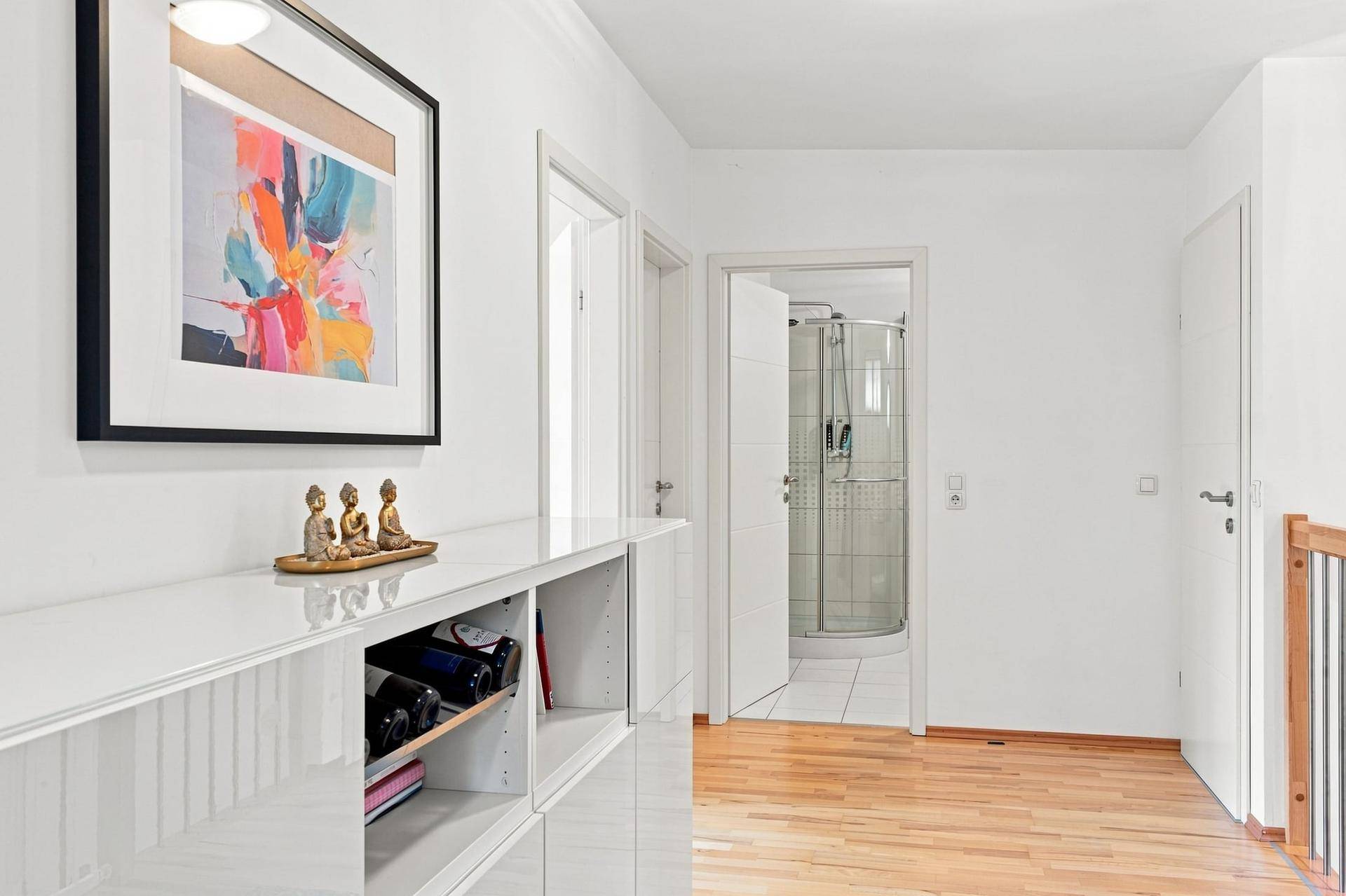 Flur mit Holzboden, moderner Dekoration und Blick in ein angrenzendes Badezimmer mit Dusche.
