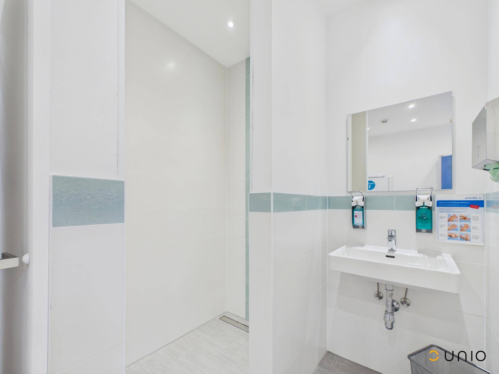 Modernes Badezimmer mit weißen Fliesen, ebenerdiger Dusche und Einzelwaschbecken.