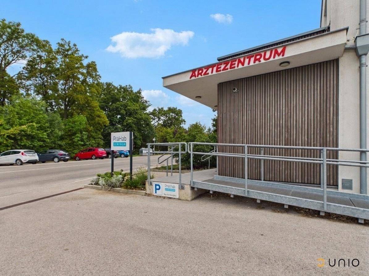 Außenansicht des Ärztezentrums mit barrierefreier Rampe und Parkplätzen im Hintergrund.