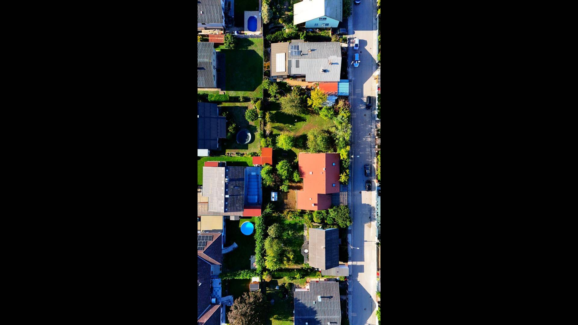 Luftaufnahme einer Wohnsiedlung mit Häusern, Gärten und Straßen.