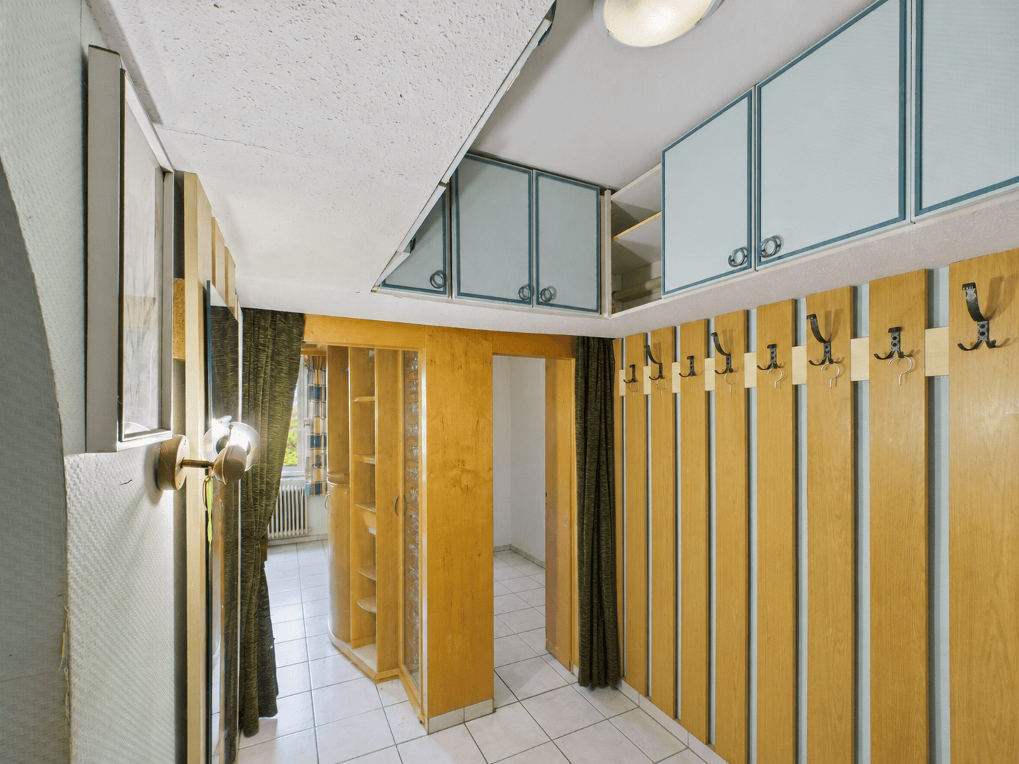Geräumiger Flur mit Garderobe, Einbauschränken und Fliesenboden im Eingangsbereich.