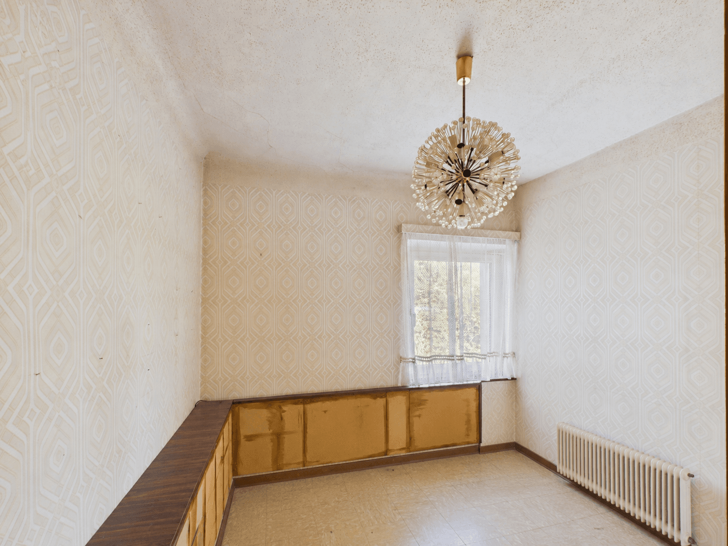 Zimmer mit gemusterter Tapete, Laminatboden und einem Fenster mit Blick ins Grüne.