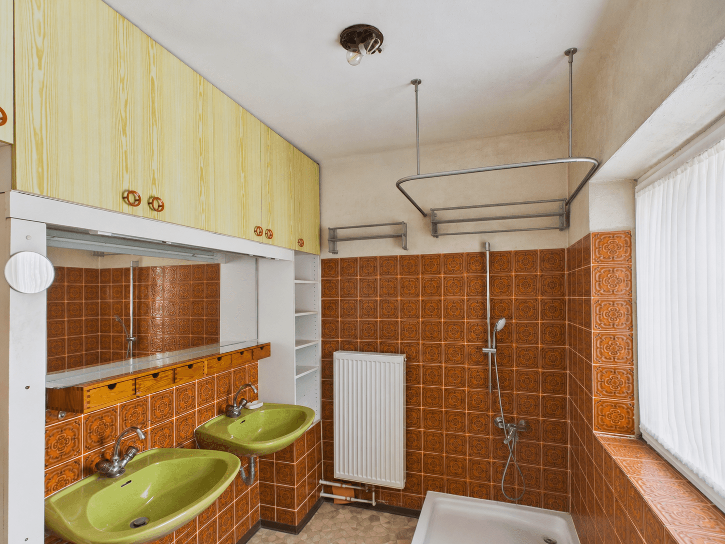 Badezimmer im Stil der 80er Jahre mit orangefarbenen Fliesen, Doppelwaschbecken und Dusche.