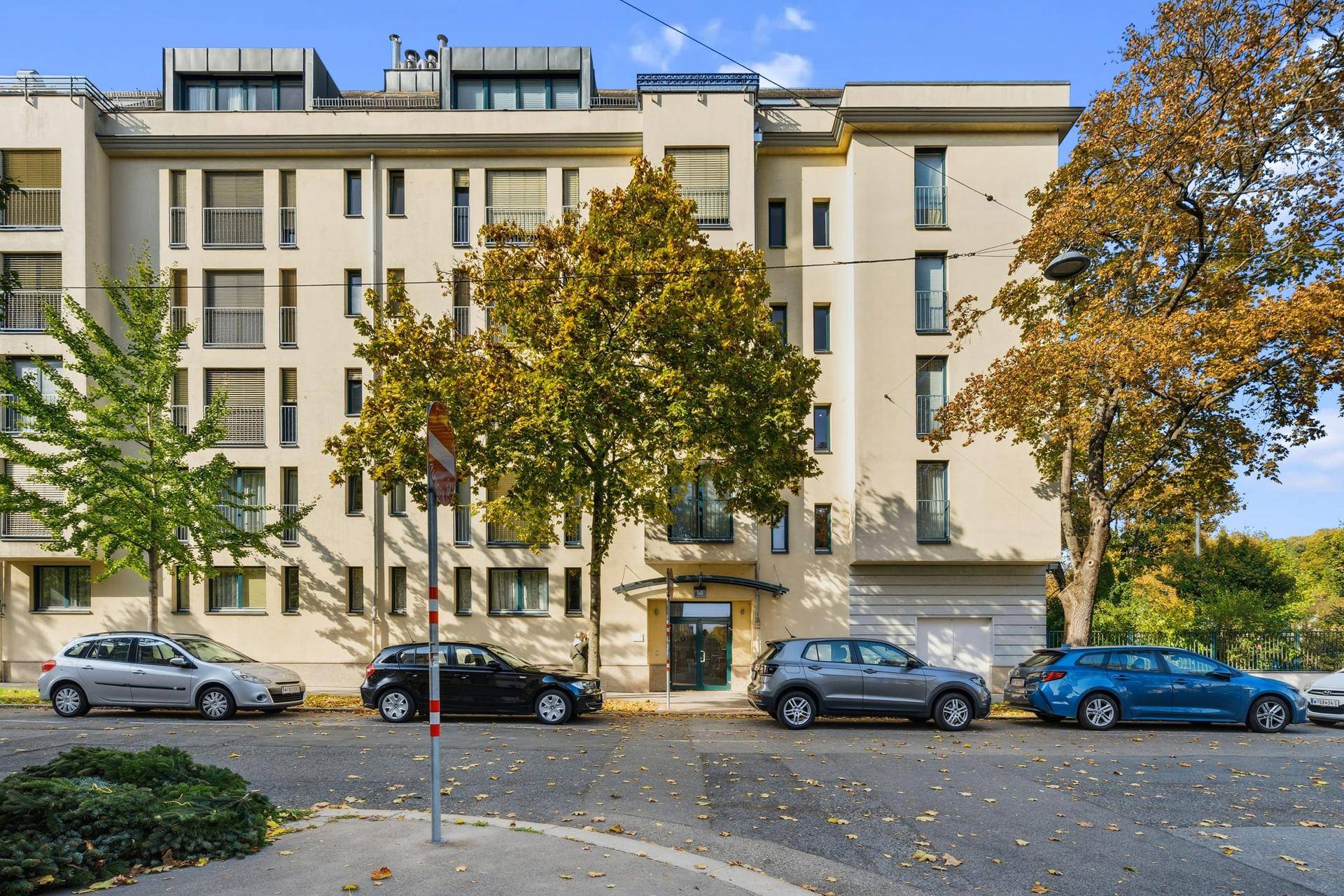 Moderne Wohngebäude-Fassade mit mehreren Balkonen und Bäumen an einer städtischen Straße.