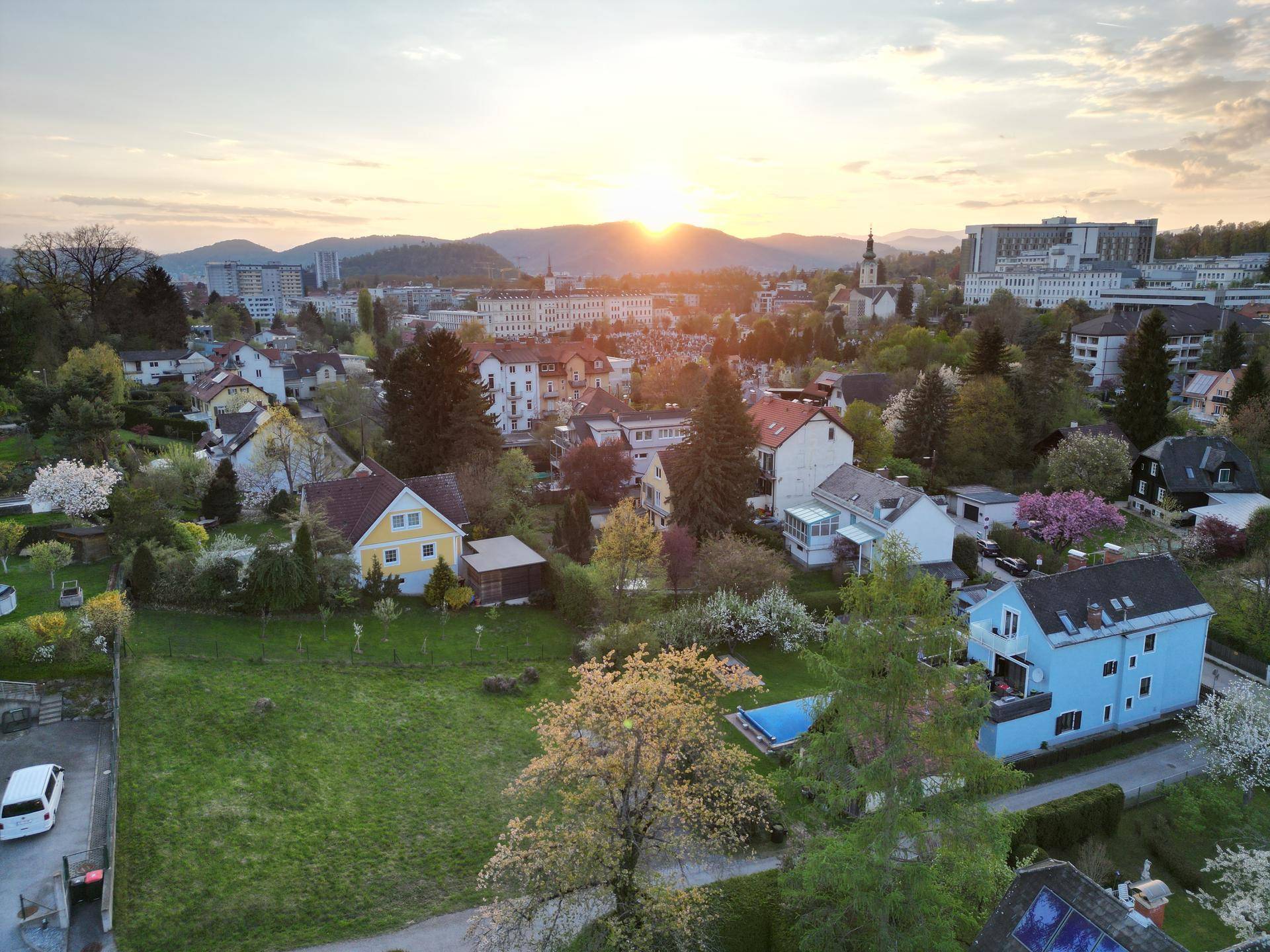 Panoramablick auf eine Wohnsiedlung bei Sonnenuntergang mit Bergen am Horizont.