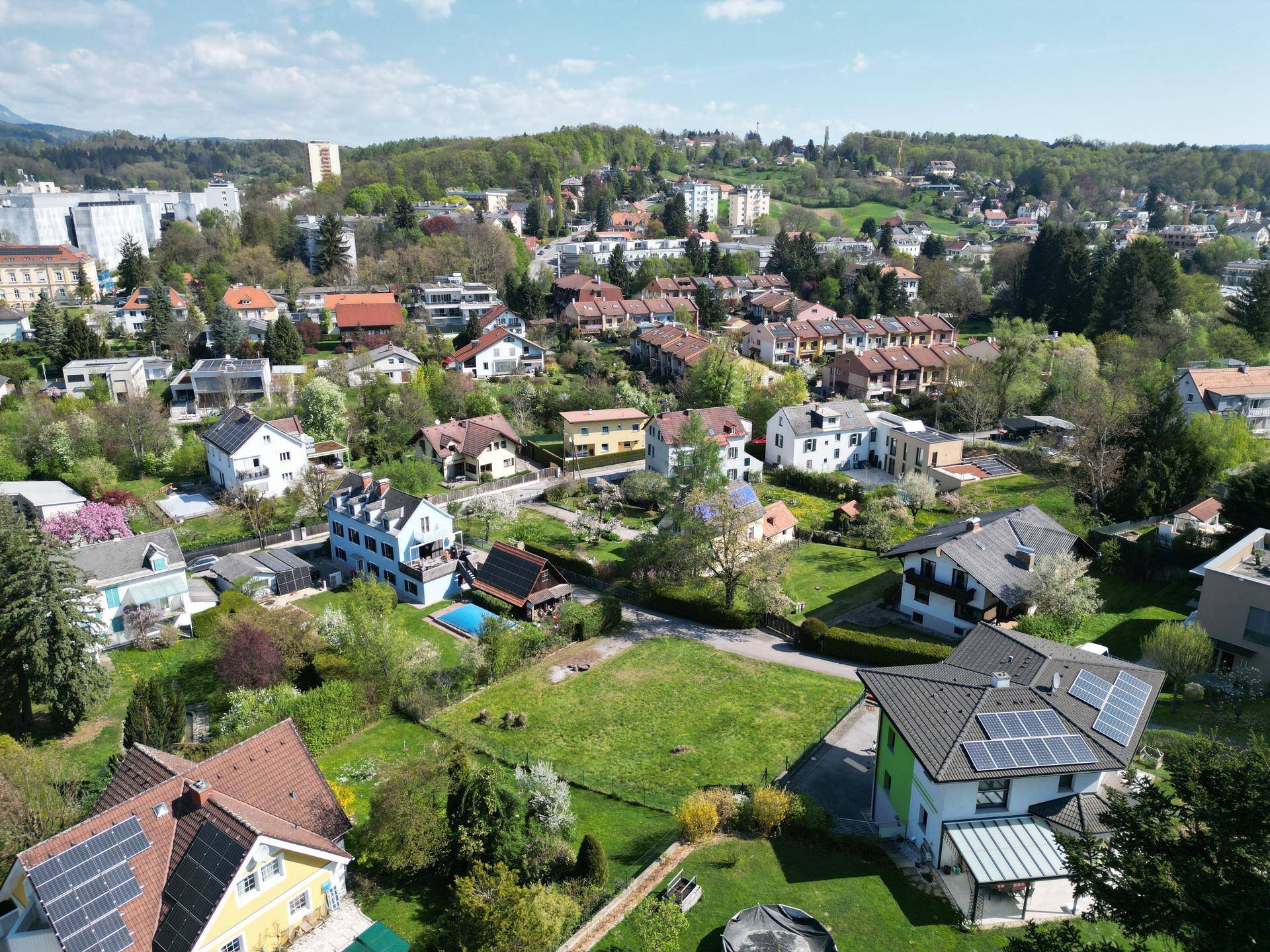Luftaufnahme einer grünen Wohngegend mit verschiedenen Häusern, einige davon mit Photovoltaikanlagen.
