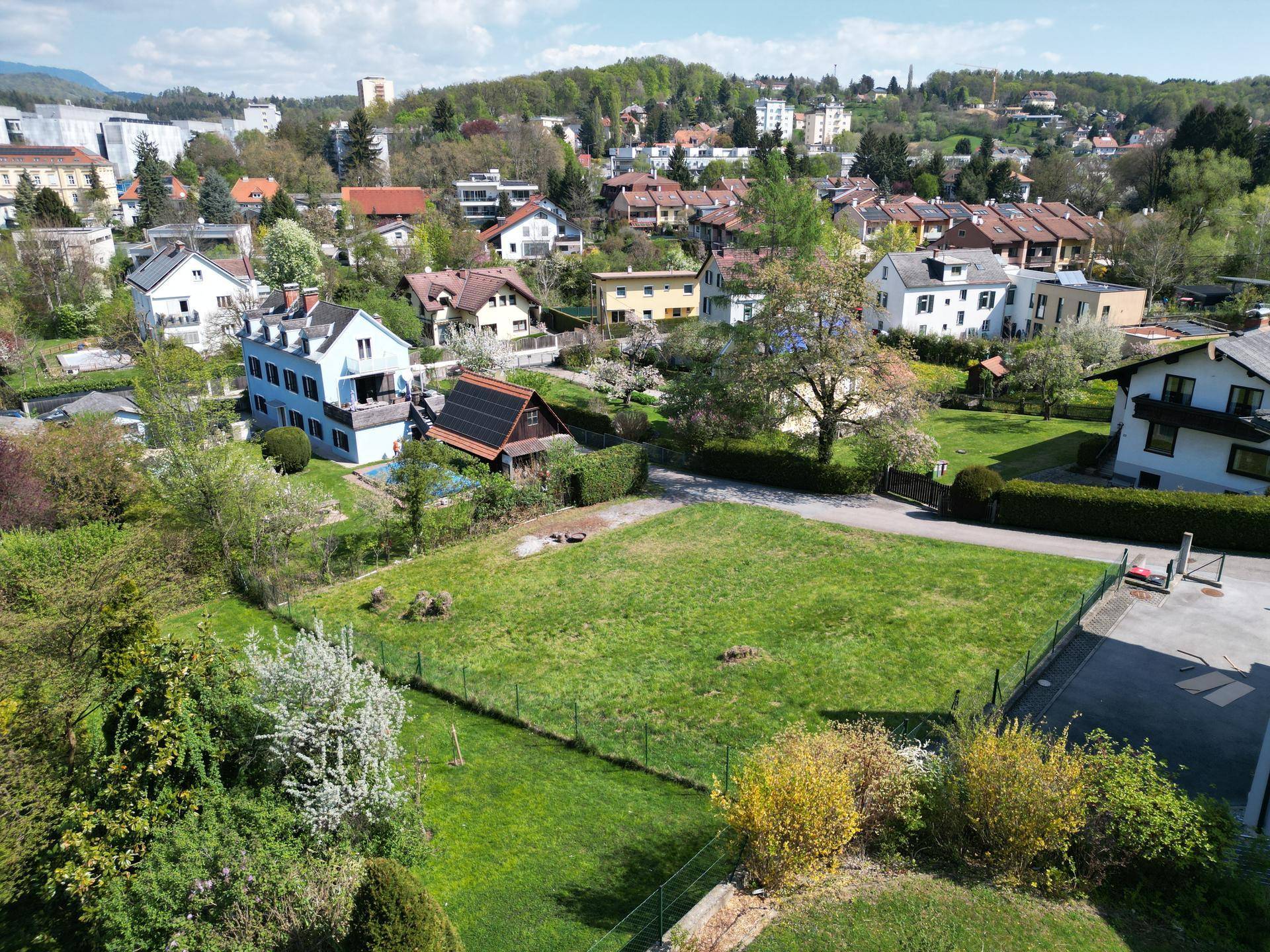 Übersicht über ein großes, eingezäuntes Grundstück mit Rasenfläche, umgeben von Wohnhäusern und Gärten.