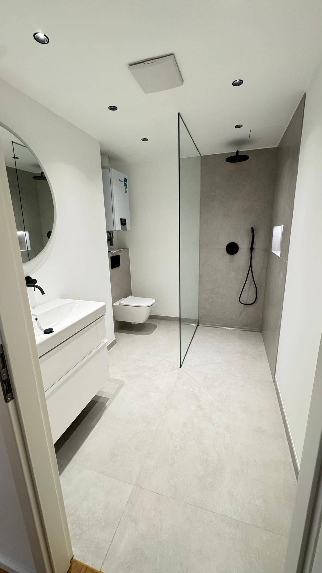 Modernes Badezimmer mit ebenerdiger Dusche, Hänge-WC und eleganten grauen Fliesen.