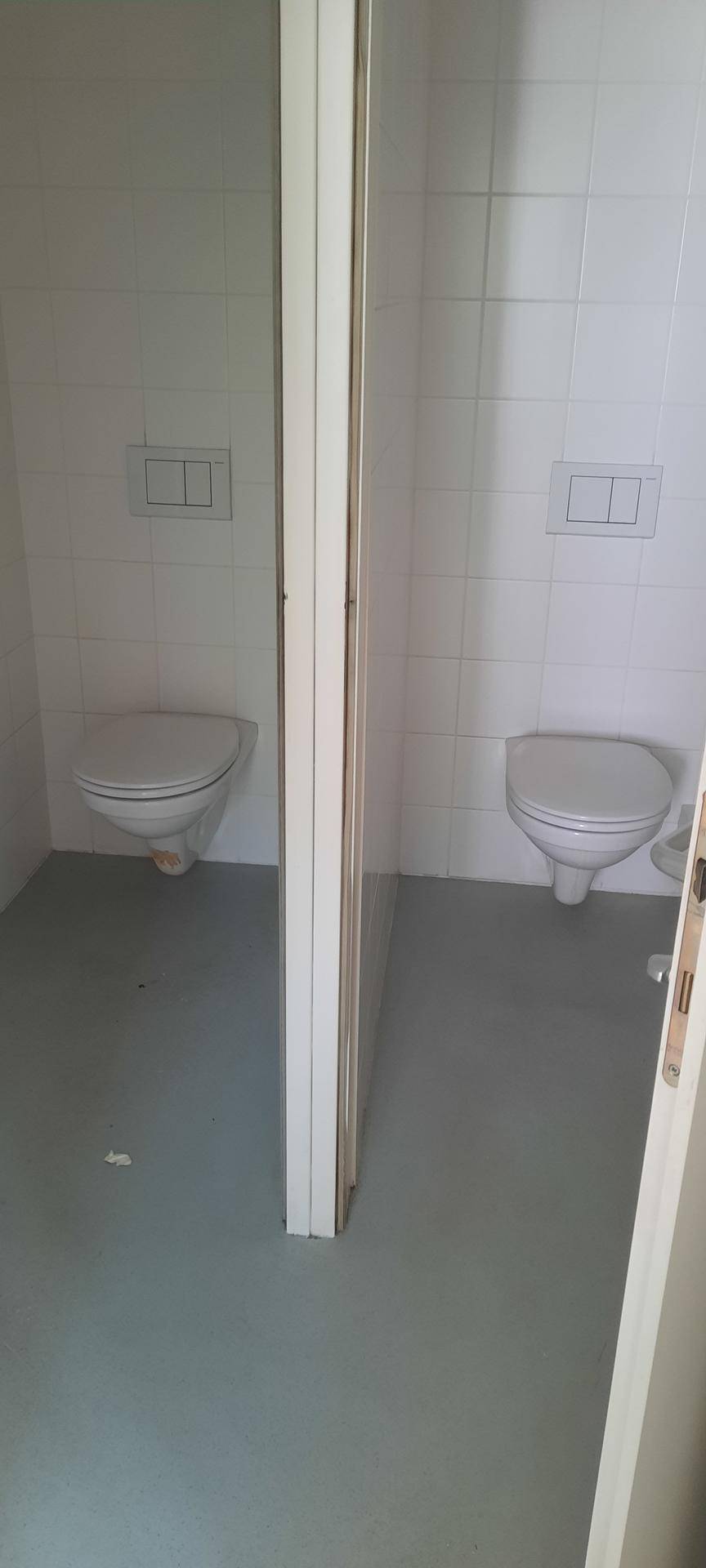 Zwei separate Toilettenkabinen mit Wand-WCs und weißen Fliesen, sauber und funktional gestaltet.