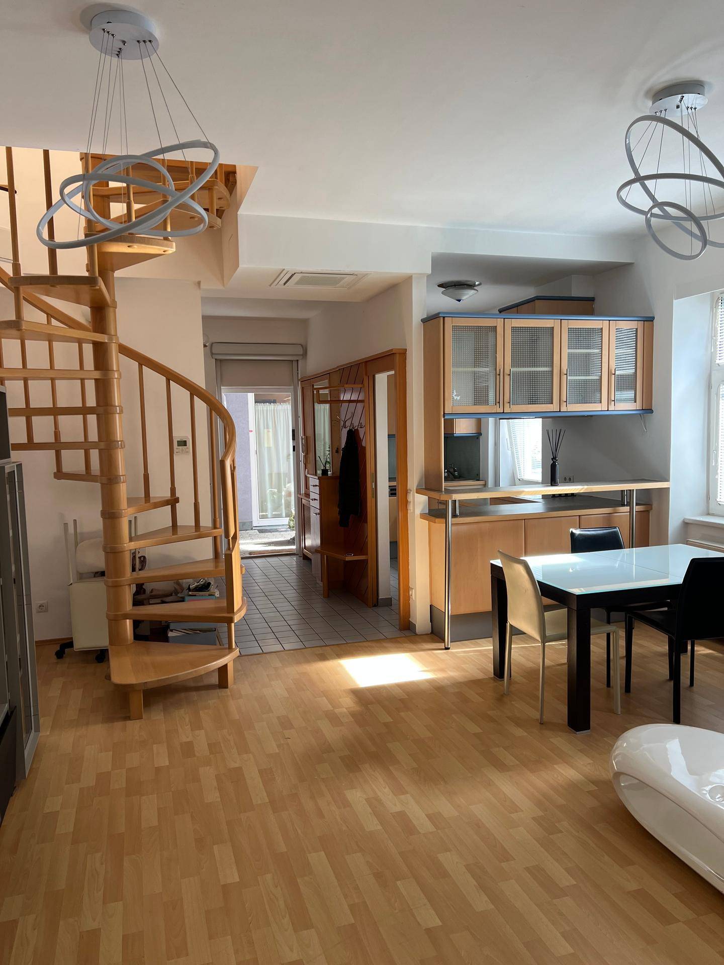 Offener Wohn-Essbereich mit Holzwendeltreppe, Esstisch und Laminatboden, hell und geräumig.