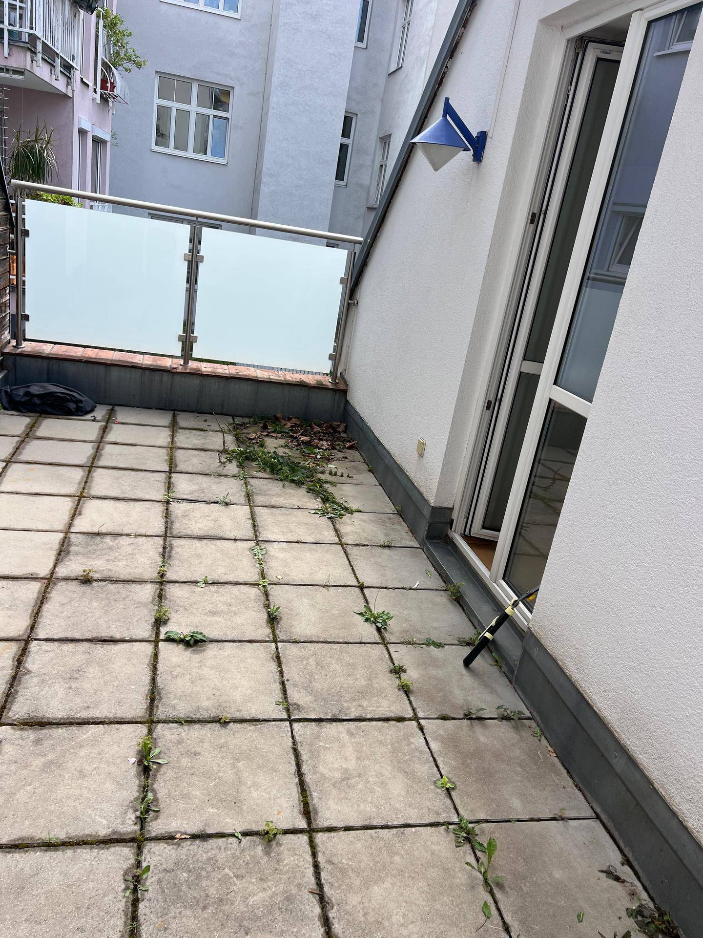 Geräumige Terrasse mit Fliesenboden, Glasgeländer und Zugang zum Innenbereich.